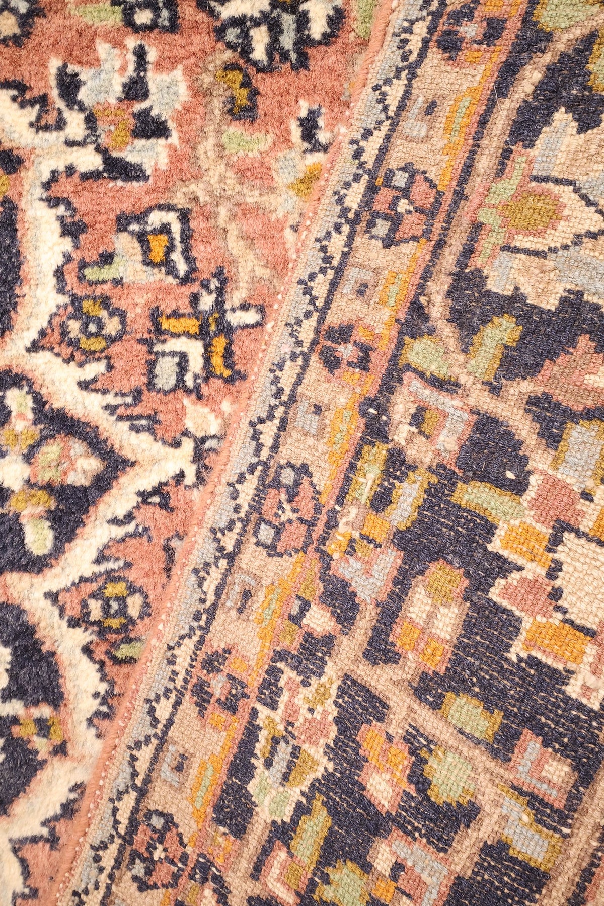 Détail en diagonale du champ rose saumon et de la bordure fleurie du tapis Agra