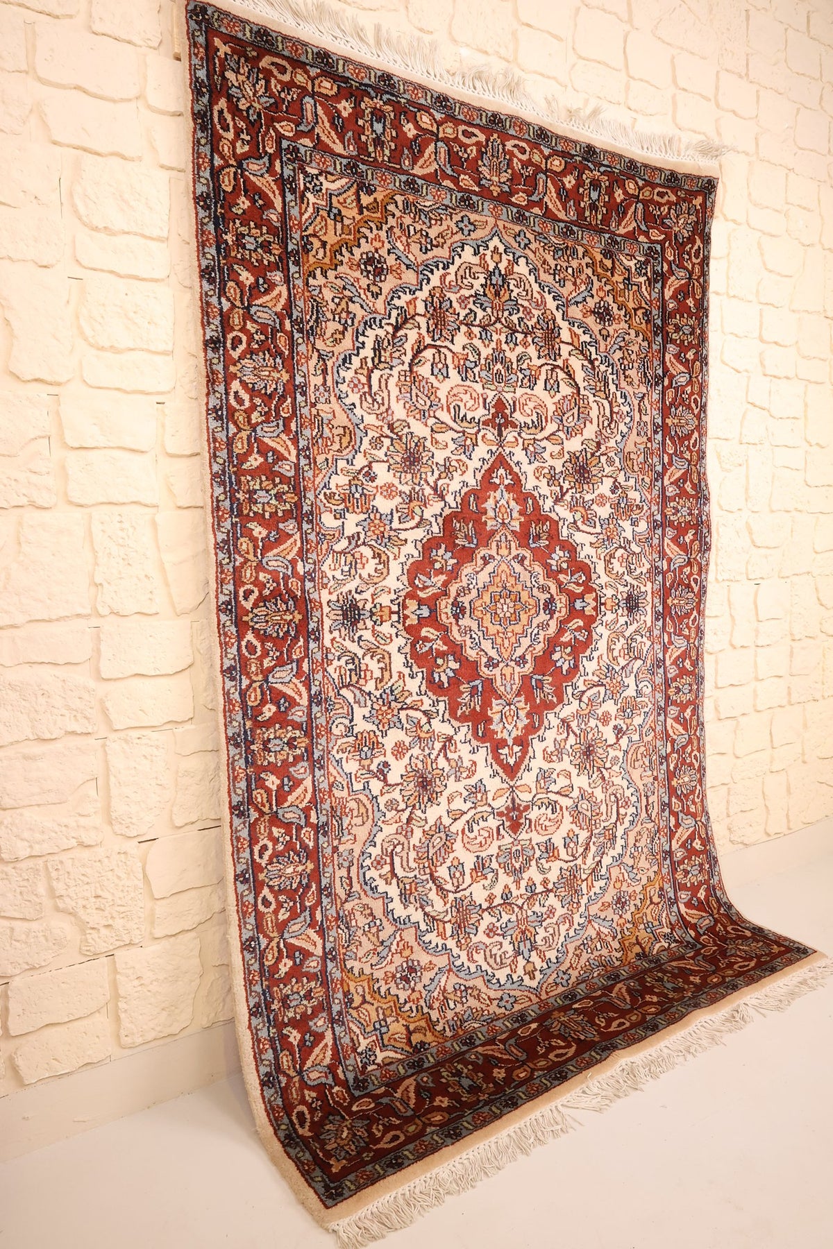 Tapis Agra rectangulaire vu de biais, bordure rouge et franges blanches