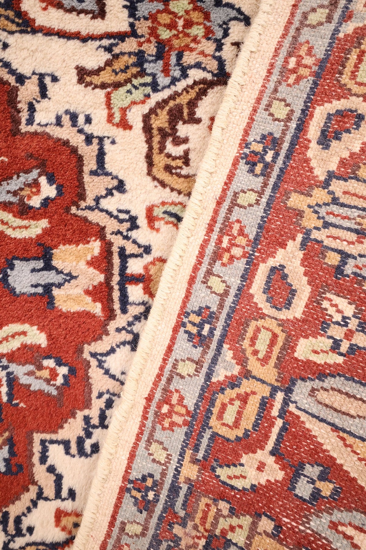Coin replié du tapis Agra beige, champ ivoire et envers de la bordure