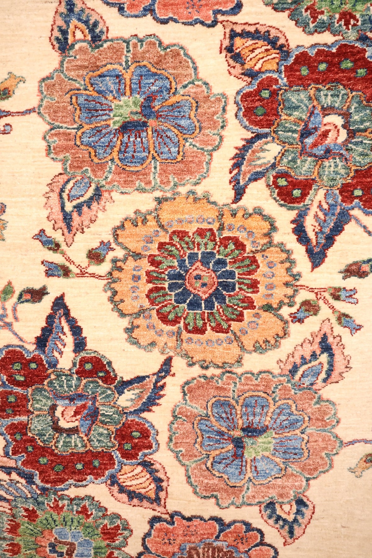Détail des palmettes bleues, rouges et orange du tapis Aryana beige