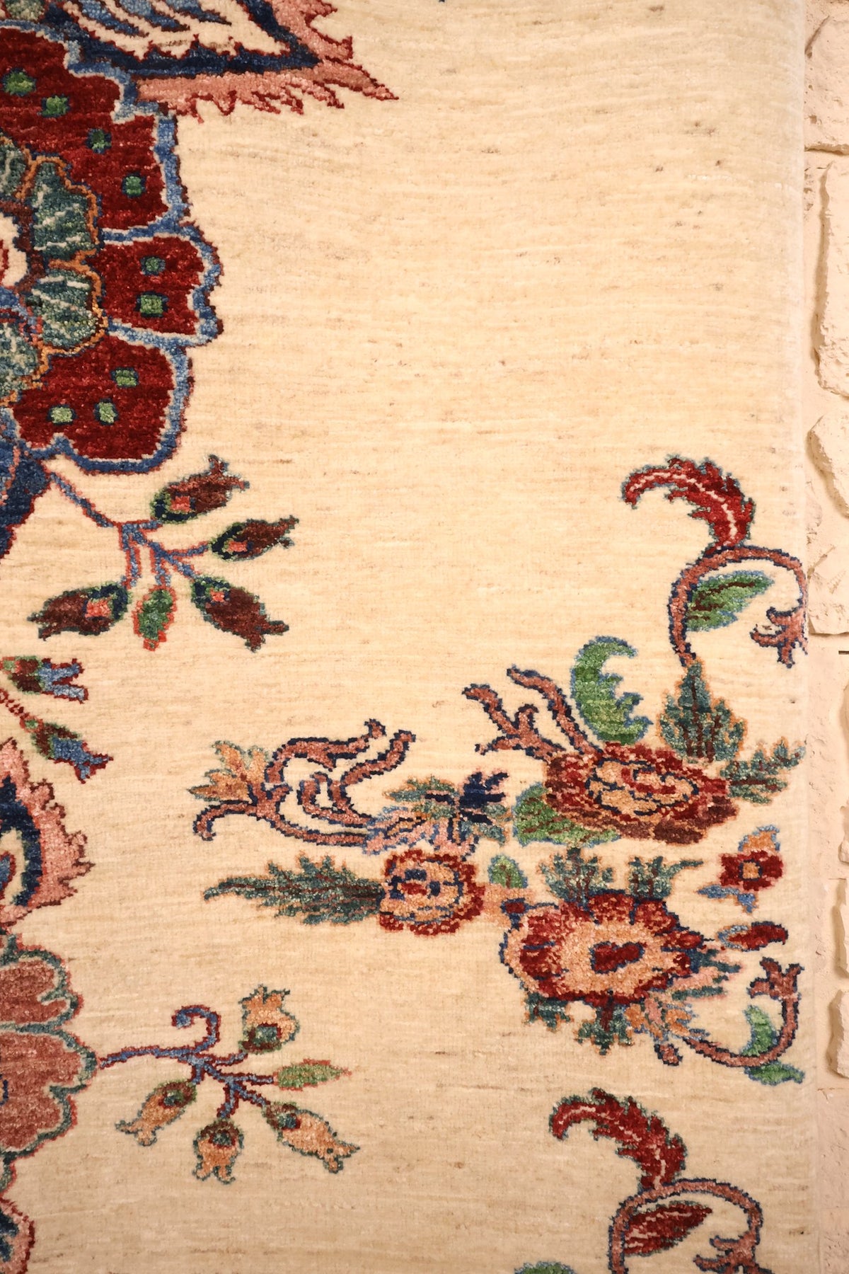 Rinceaux feuillus et bouquet d'angle sur le champ ivoire du tapis Aryana