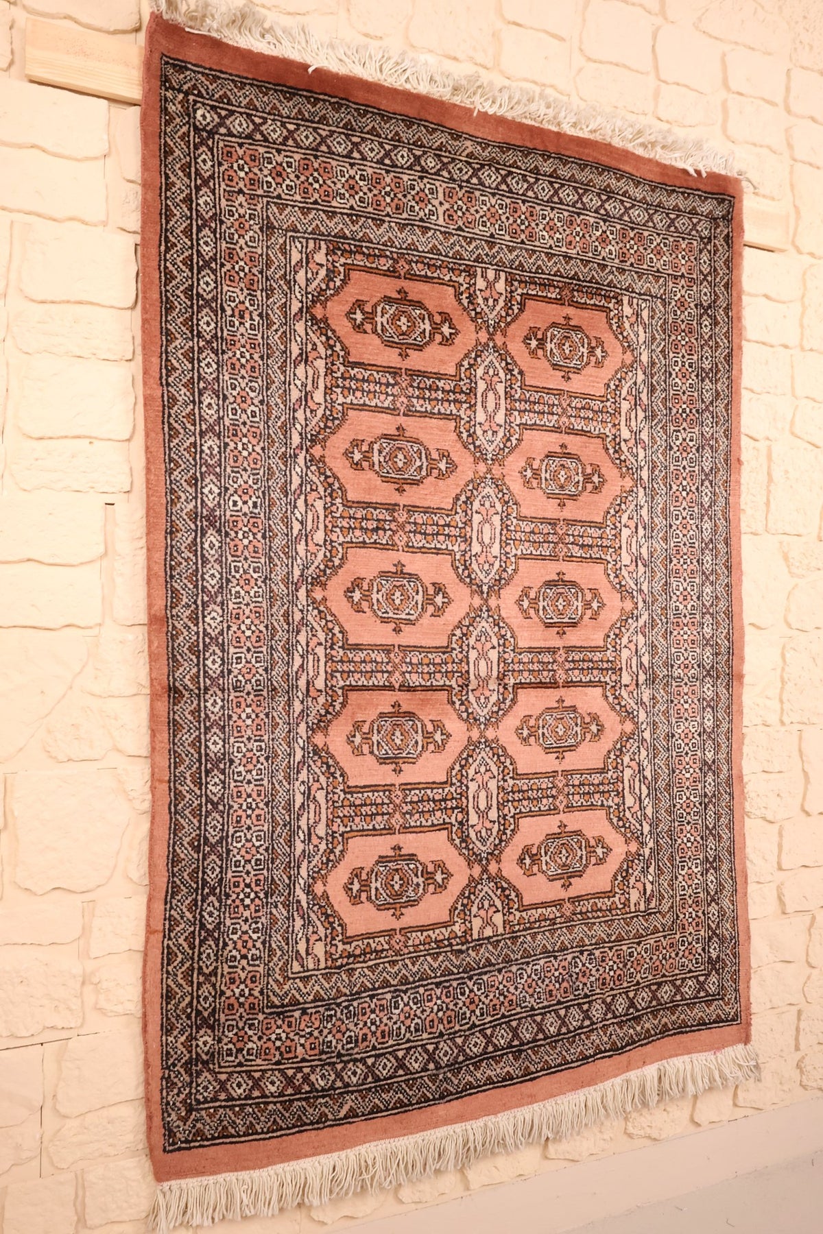 Tapis Boukhara rose en laine, vue de biais montrant les deux colonnes de médaillons