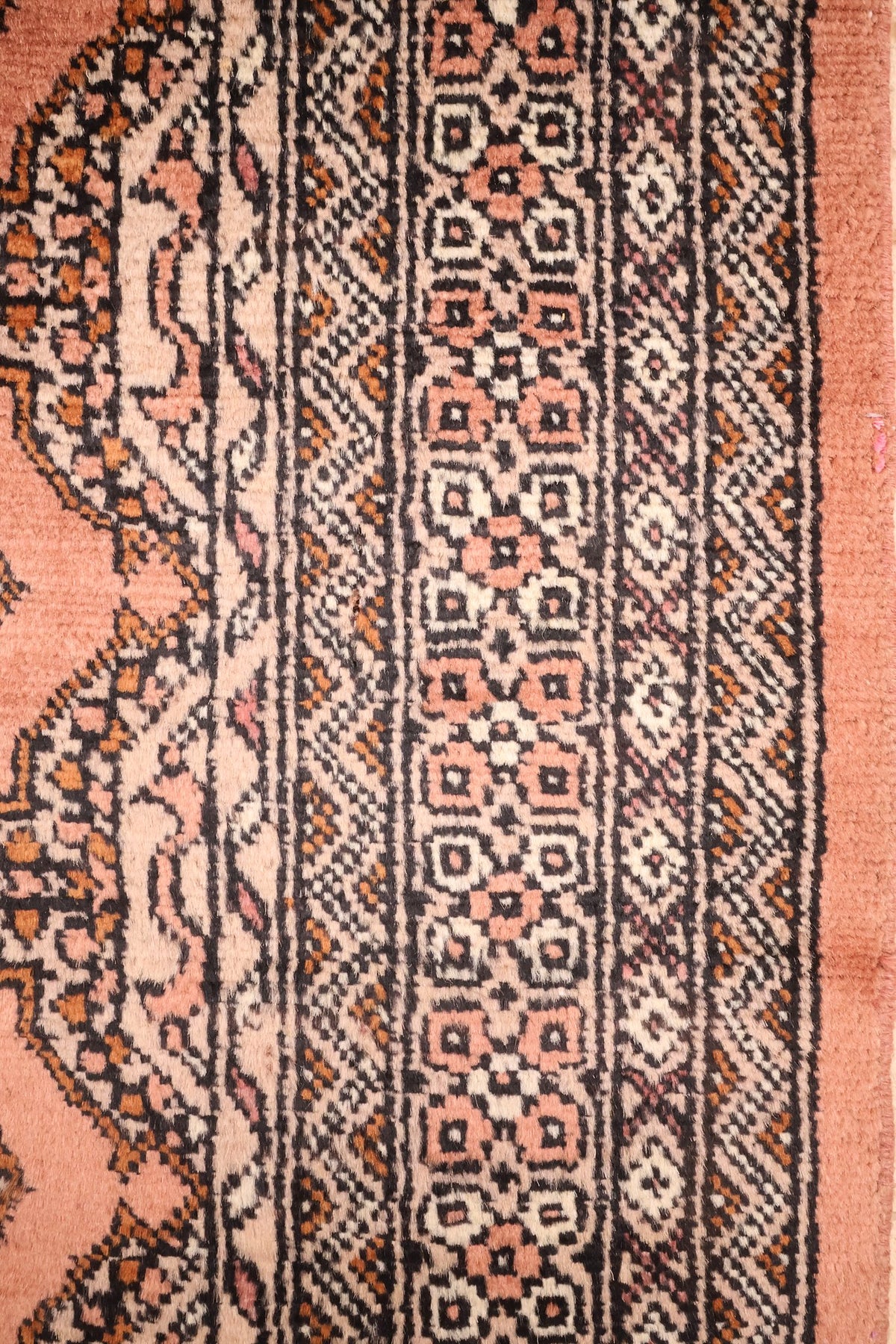 Bordures du tapis Boukhara : rangées de carrés et losanges crochetés noir, écru et rose