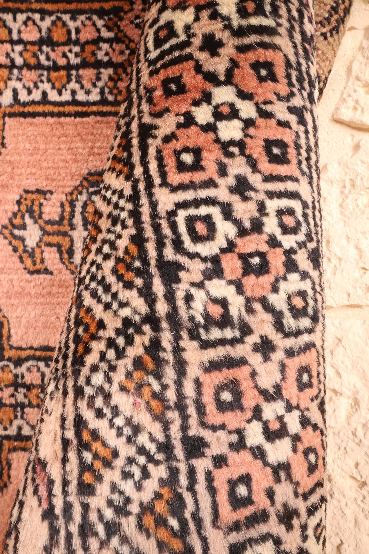 Coin replié du Boukhara rose, bordure à losanges et souplesse de la laine nouée main