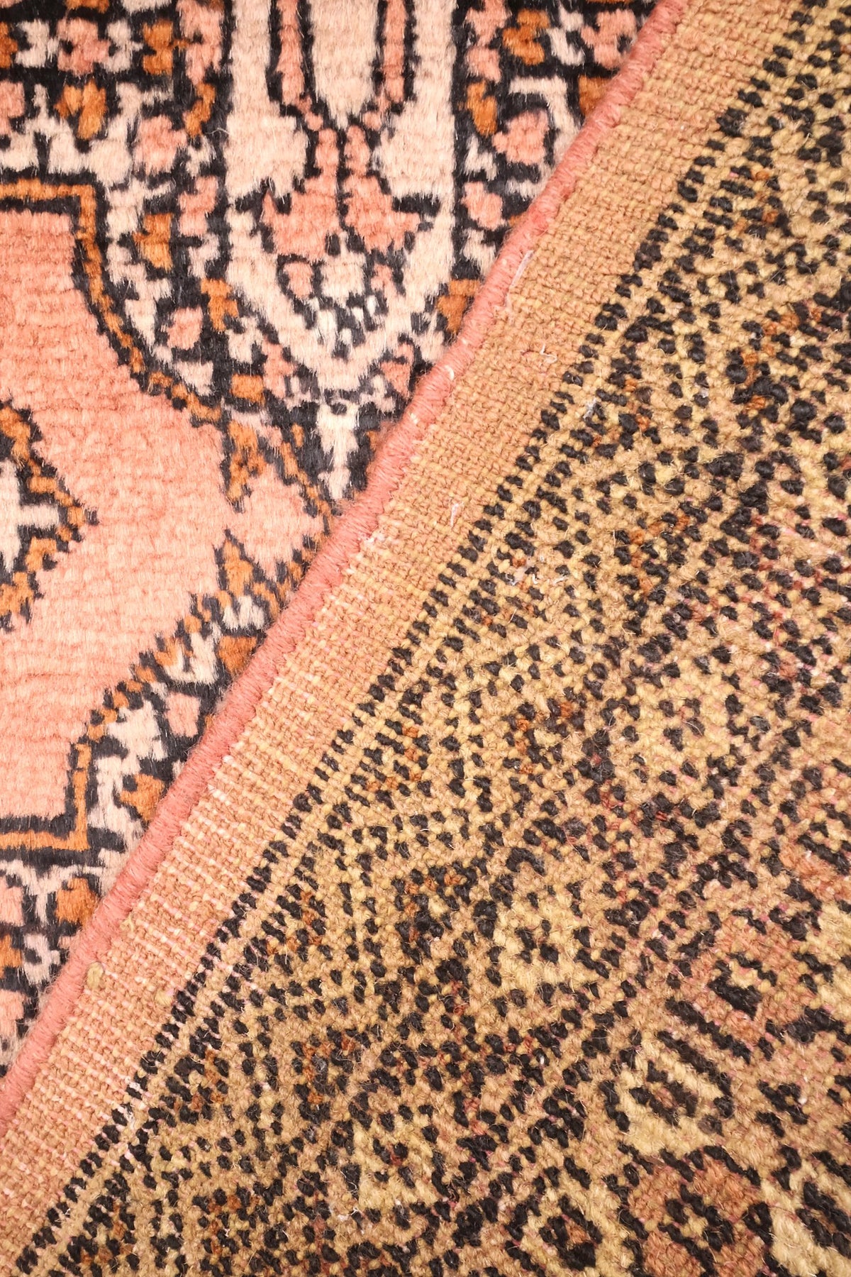 Envers du tapis Boukhara en laine, nœuds serrés visibles près de la lisière