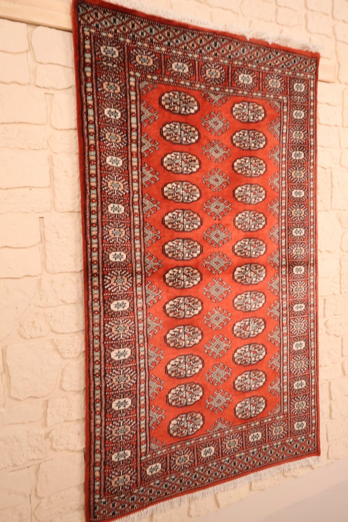 Tapis Boukhara en laine noué à la main, vue de biais sur le champ rouge brique