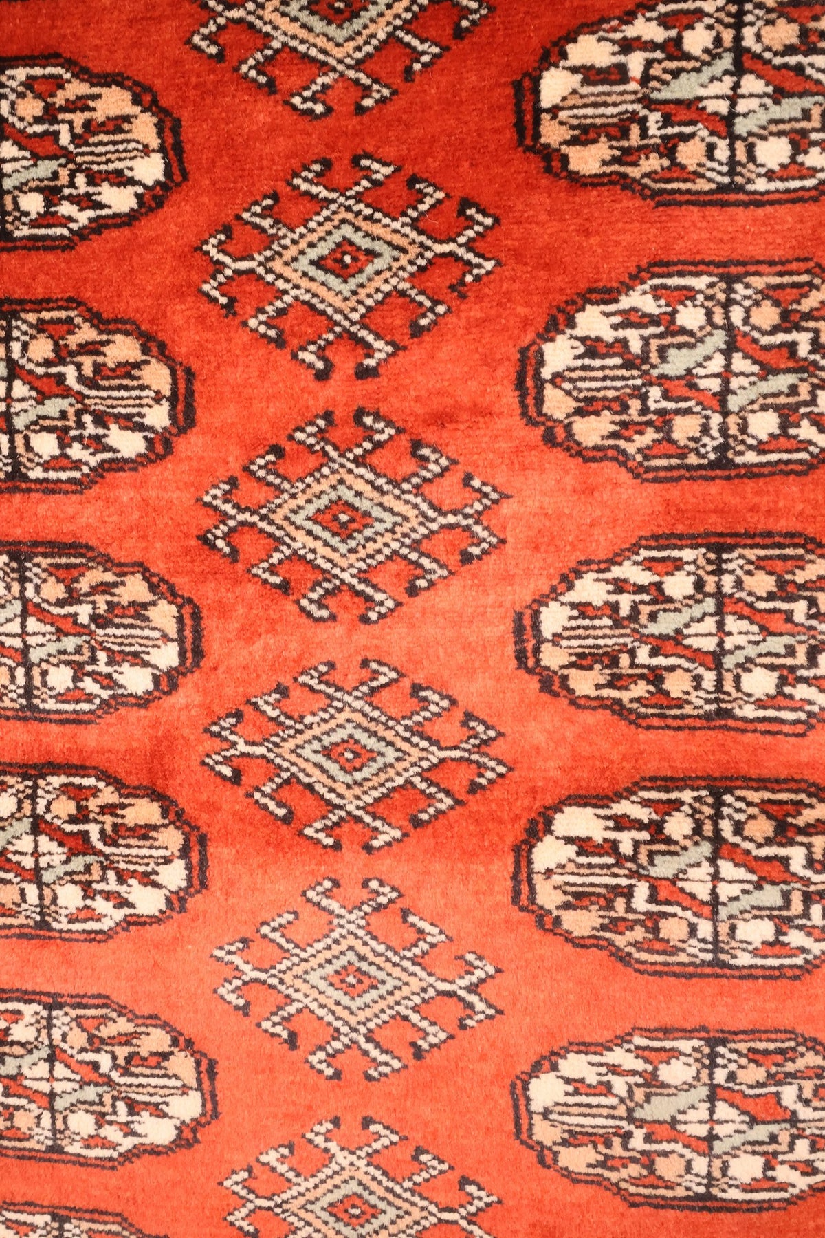 Détail des guls octogonaux et losanges crochetés beige du tapis Boukhara rouge