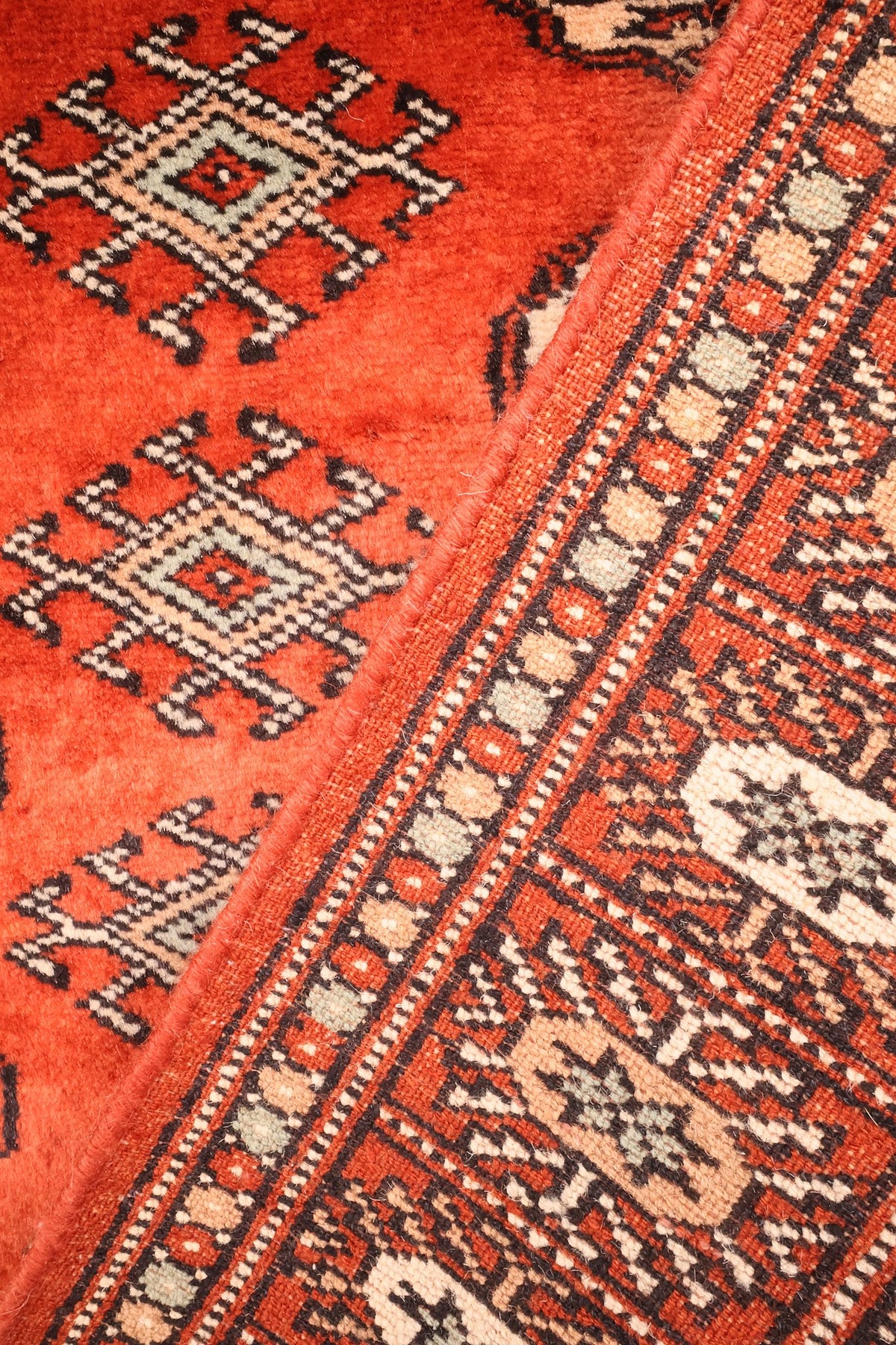 Passage du champ rouge aux contre-bordures géométriques du tapis Boukhara