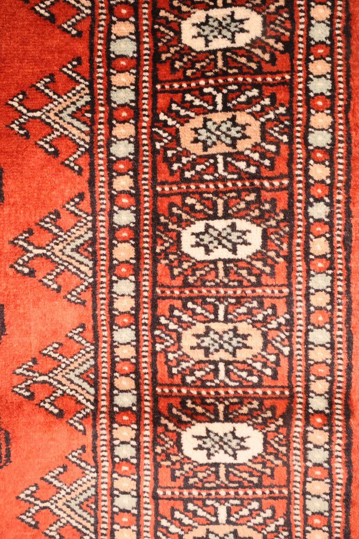 Bordure à cartouches ovales ivoire et rosés du tapis Boukhara, contours noirs