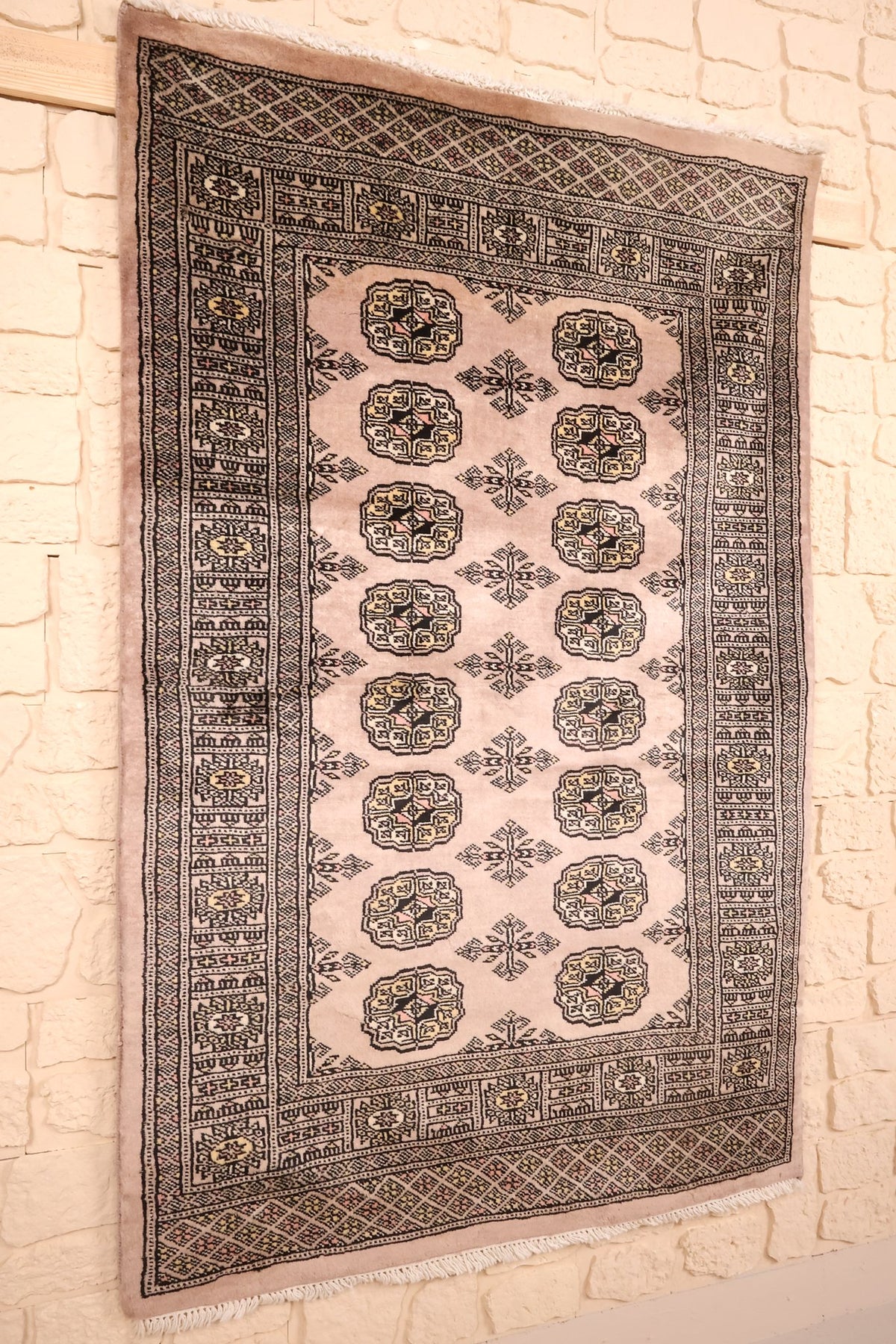 Vue de biais du tapis Boukhara beige et noir, bordures multiples visibles