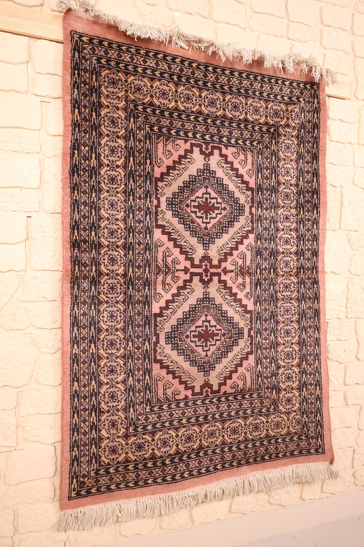 Tapis Boukhara rose et noir vu de biais, encadrement de bordures multiples