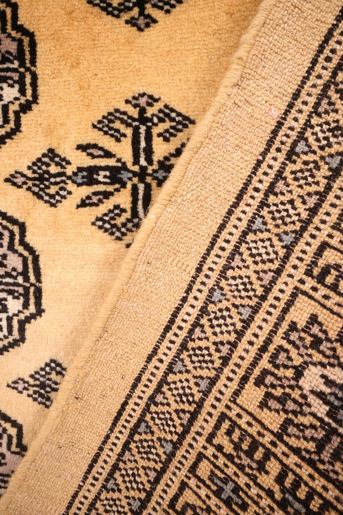 Envers du tapis Boukhara en laine, nœuds visibles le long de la bordure