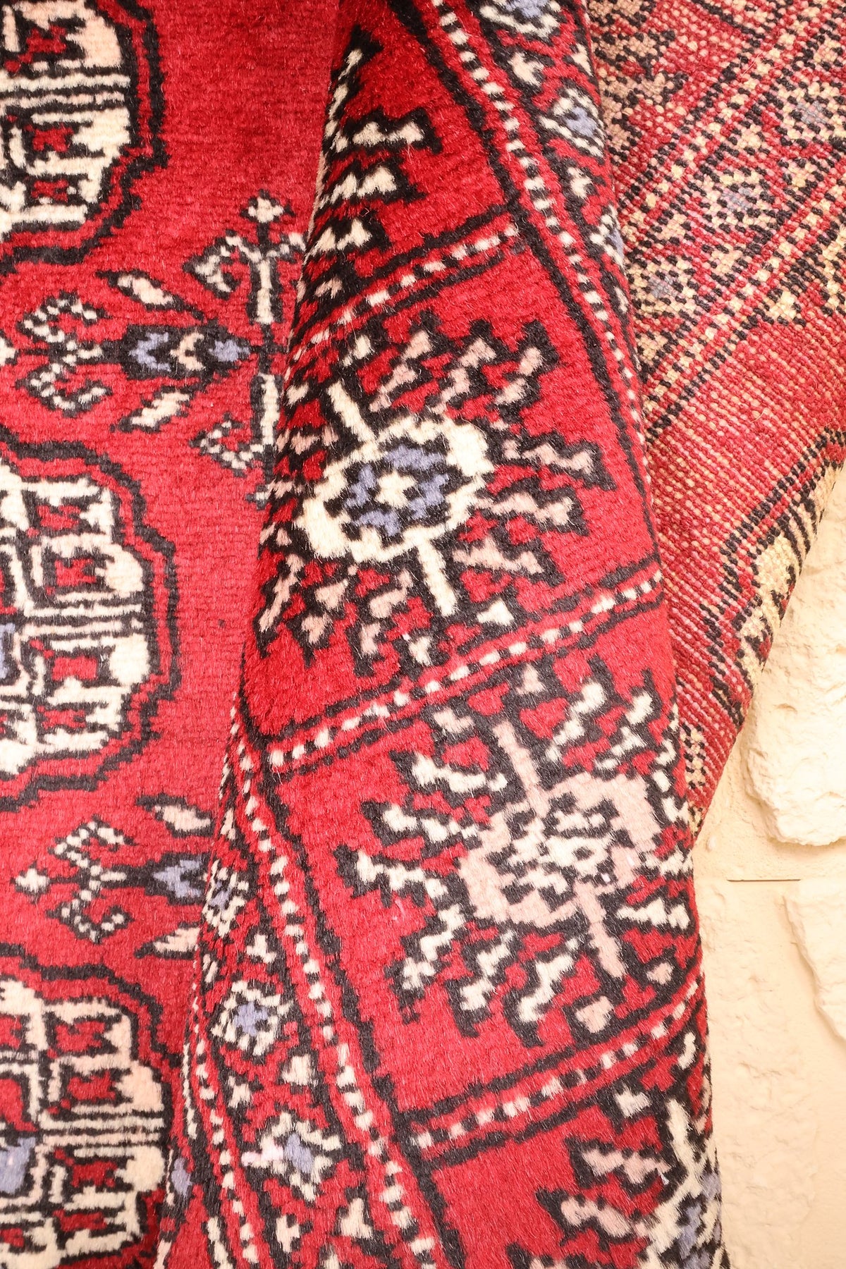 Coin replié du tapis Boukhara, décor répétitif et dos du tissage côte à côte