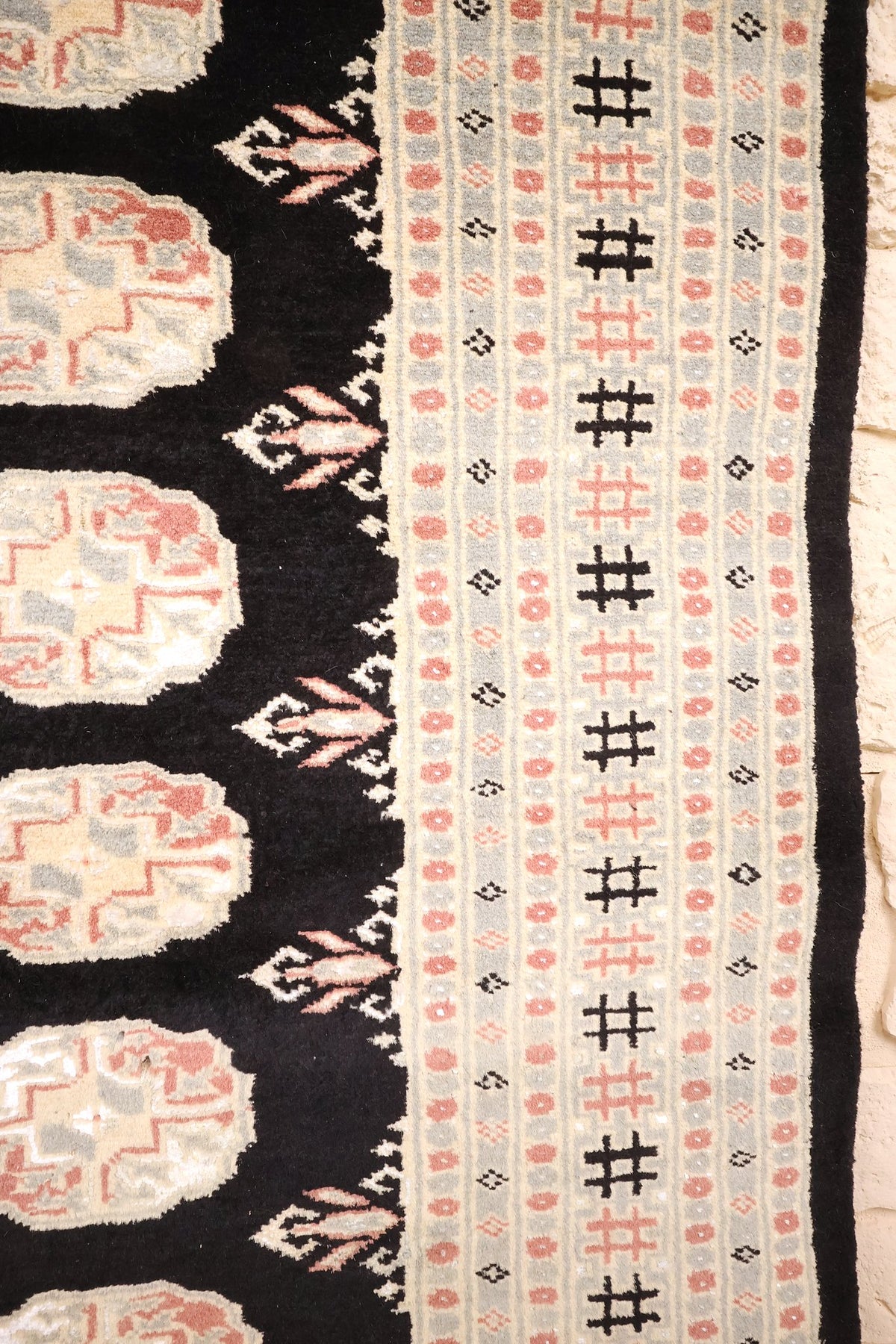Bordure beige et grise du tapis Boukhara, croisillons noirs et rosettes roses