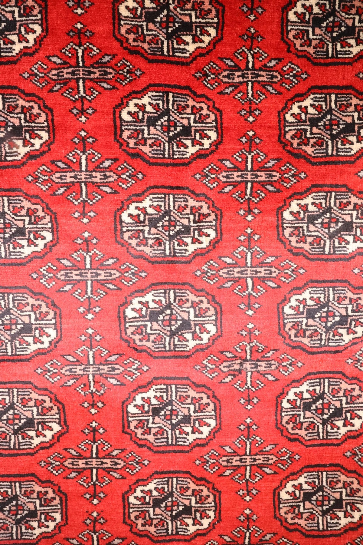 Détail des guls octogonaux beige, noir et rose du tapis Boukhara rouge