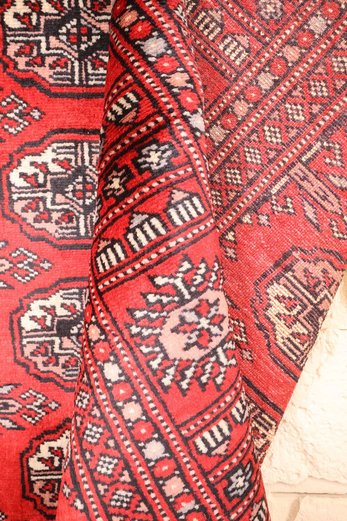 Coin replié du tapis Boukhara en laine, bordures et motifs répétitifs