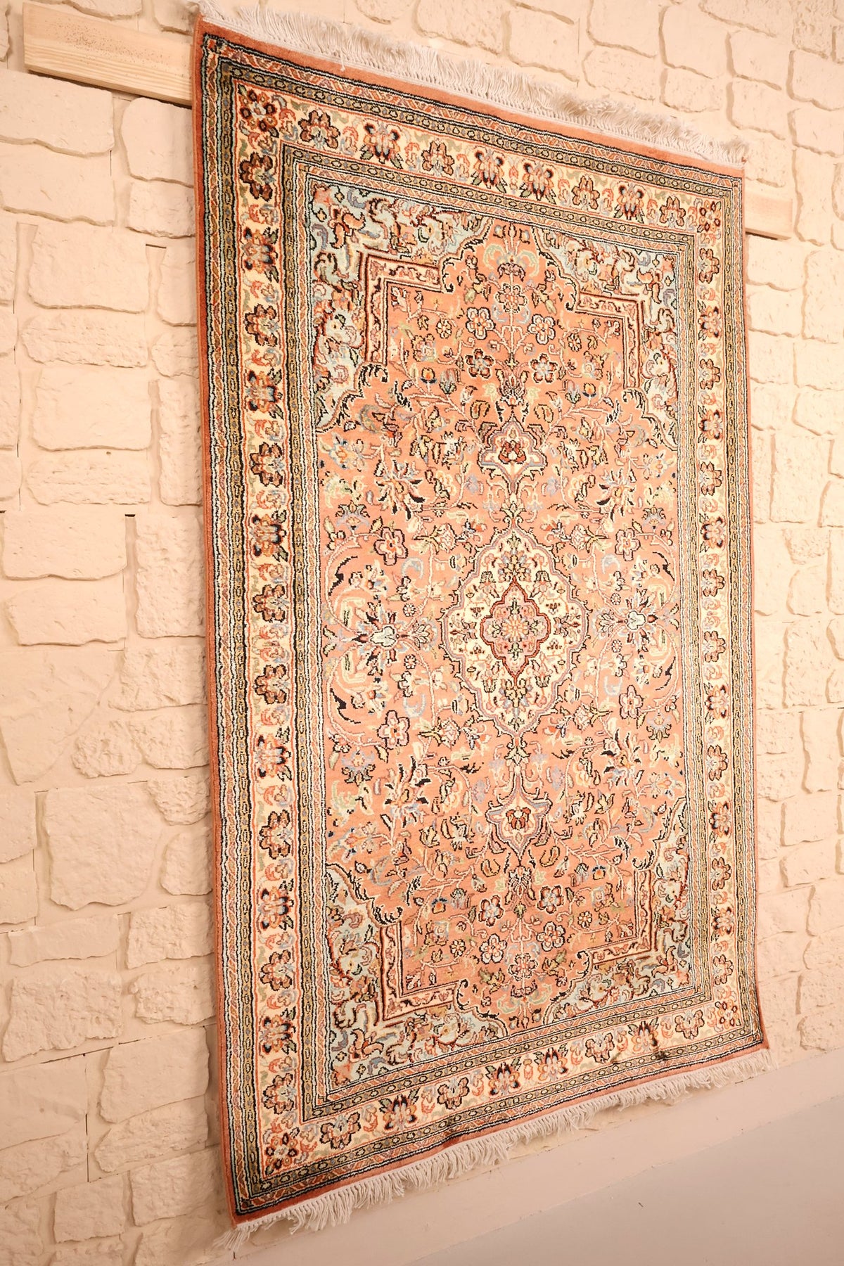 Tapis Cachemire rose en soie artificielle, vue de biais sur le champ fleuri et ses bordures