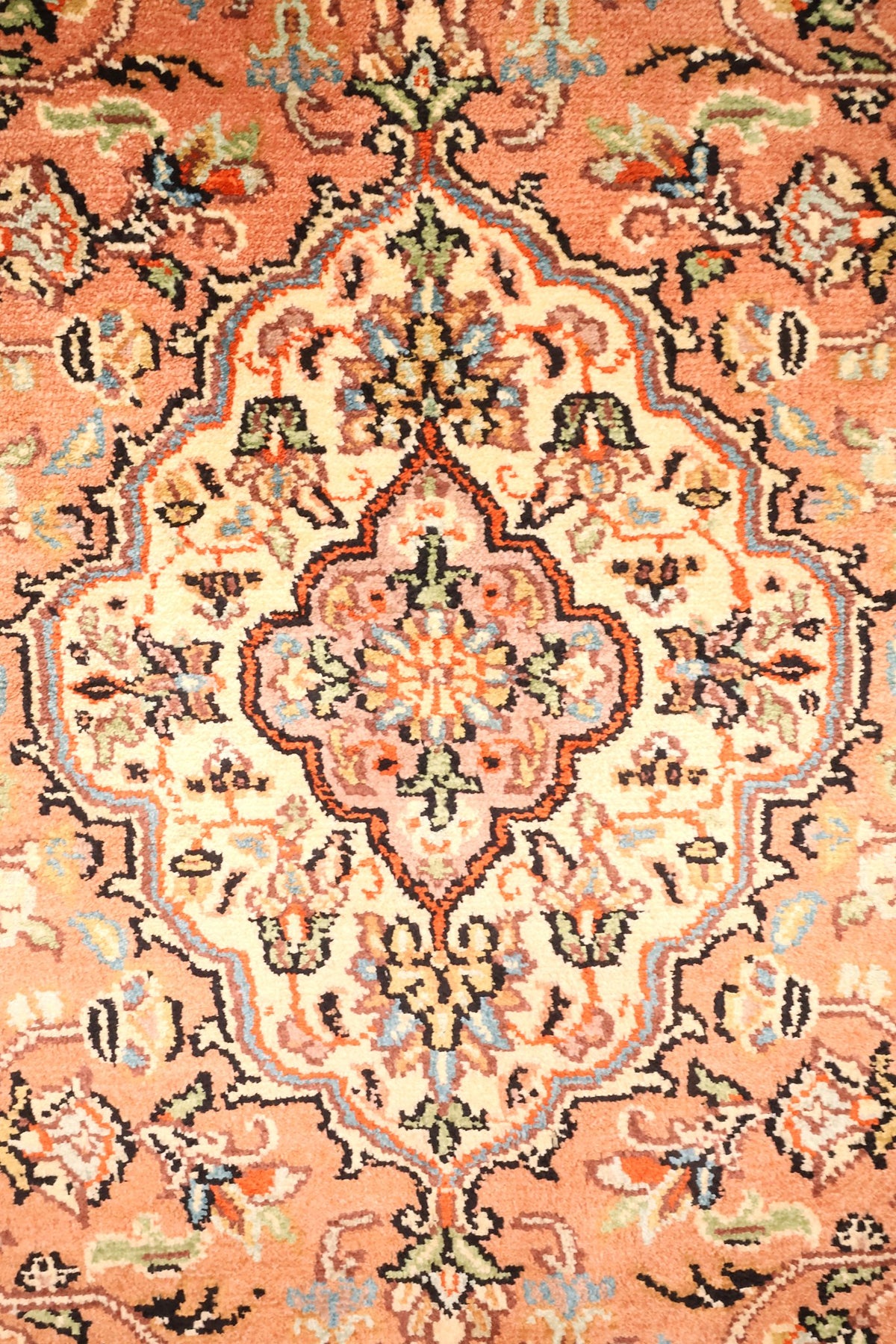 Détail du médaillon central ivoire à contour lobé sur champ rose saumon, tapis Cachemire