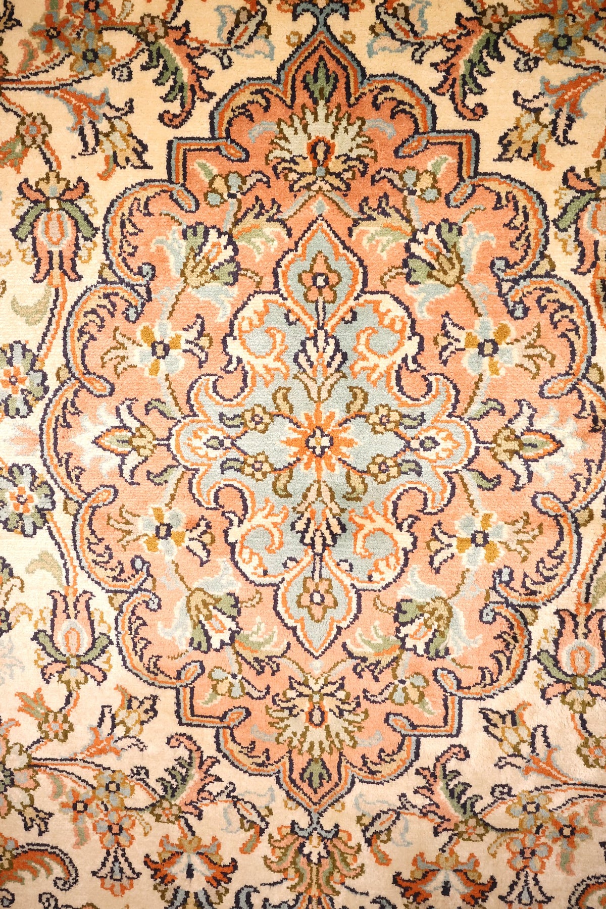 Détail du médaillon rose saumon à cœur bleu clair du tapis Cachemire en soie