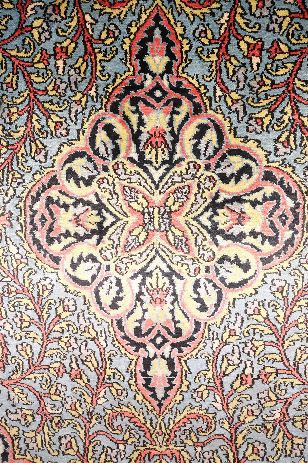 Détail du médaillon polylobé noir, rose et jaune du tapis Cachemire bleu
