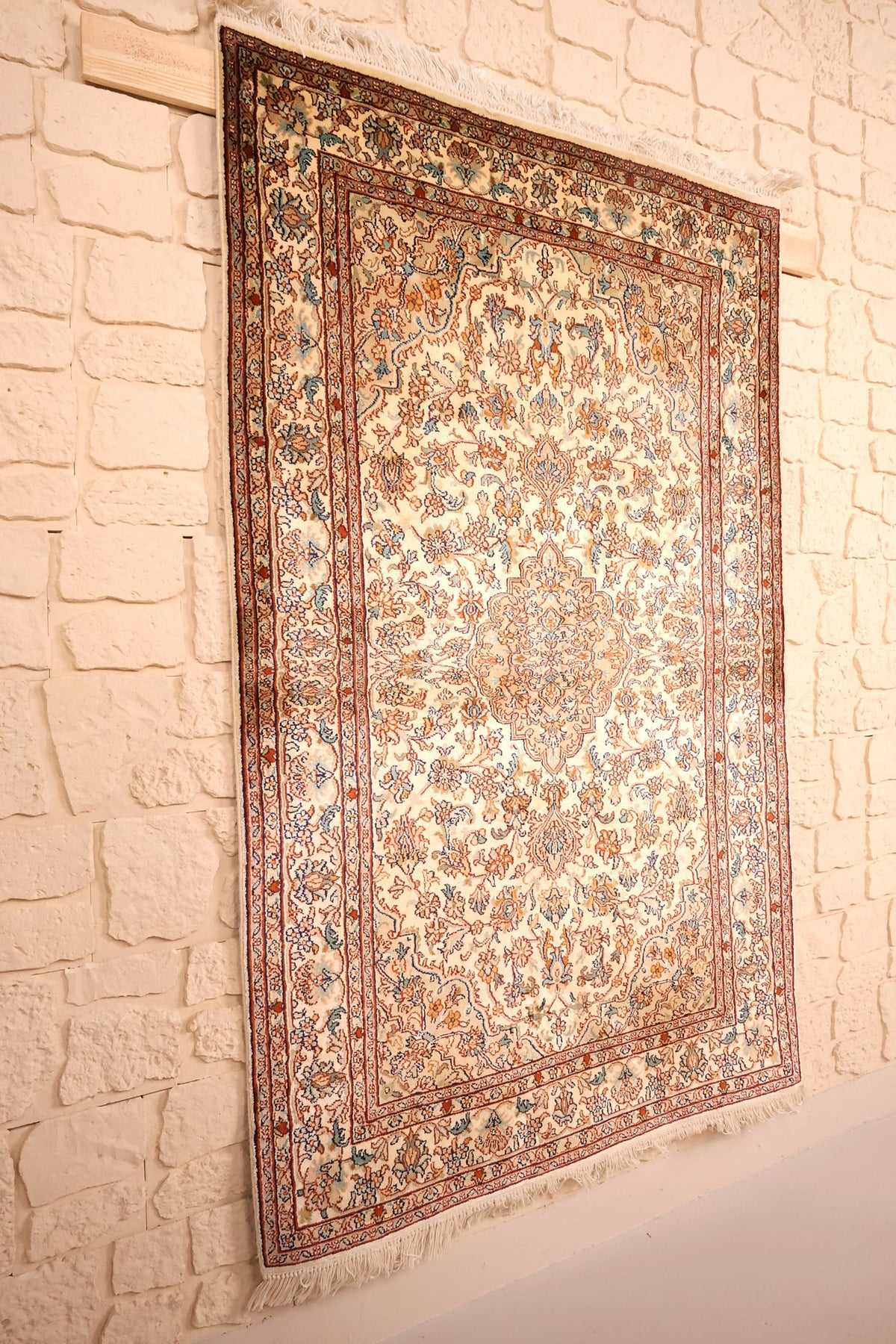 Tapis Cachemire beige et orange vu de biais, bordures fleuries et champ ivoire