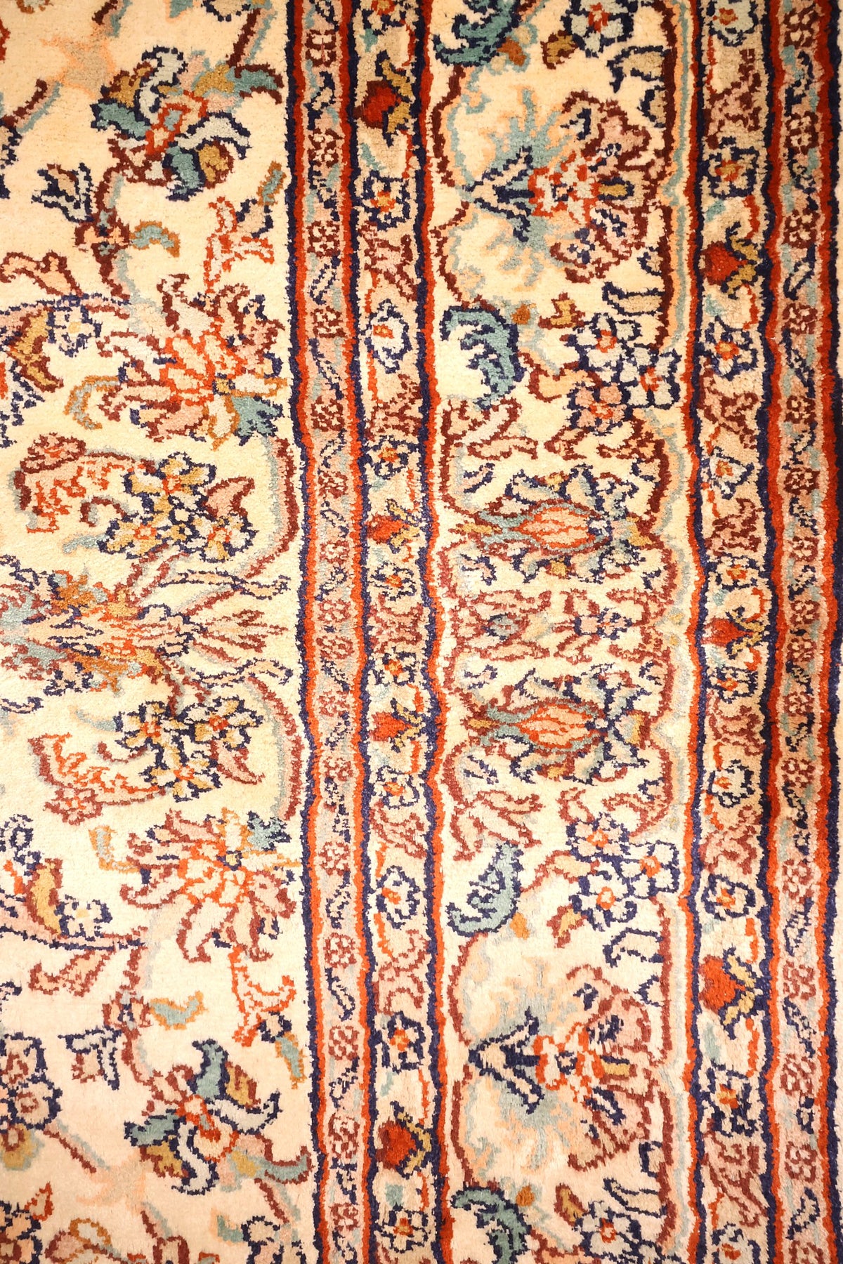 Bordure beige à fleurs et liserés bleu foncé et rouge du tapis Cachemire