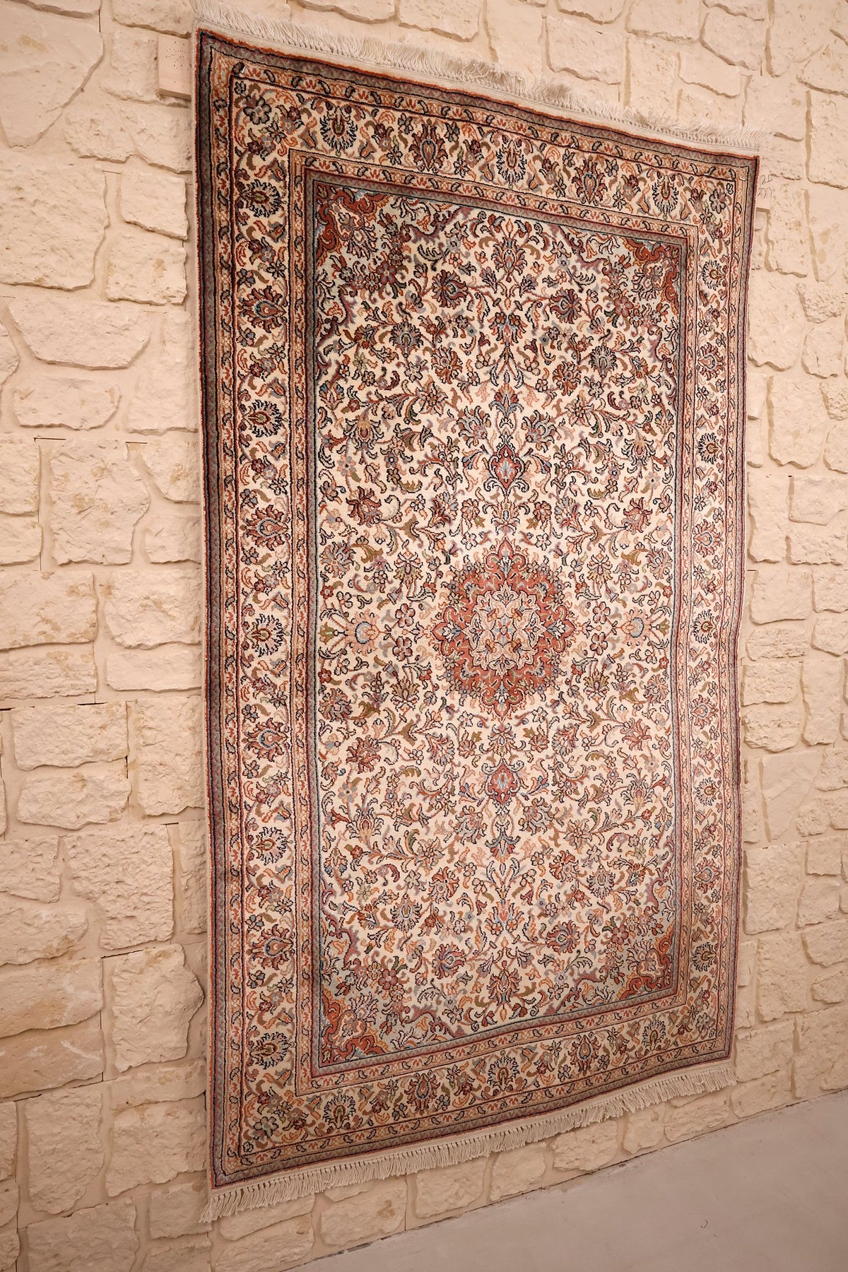 Tapis Cachemire en soie beige vu de biais, champ fleuri et franges claires