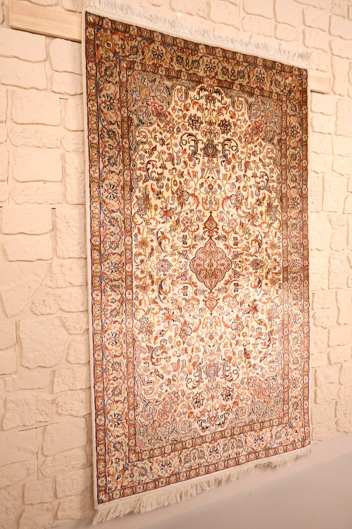 Tapis Cachemire beige et orange vu de biais, médaillon central et bordures fleuries