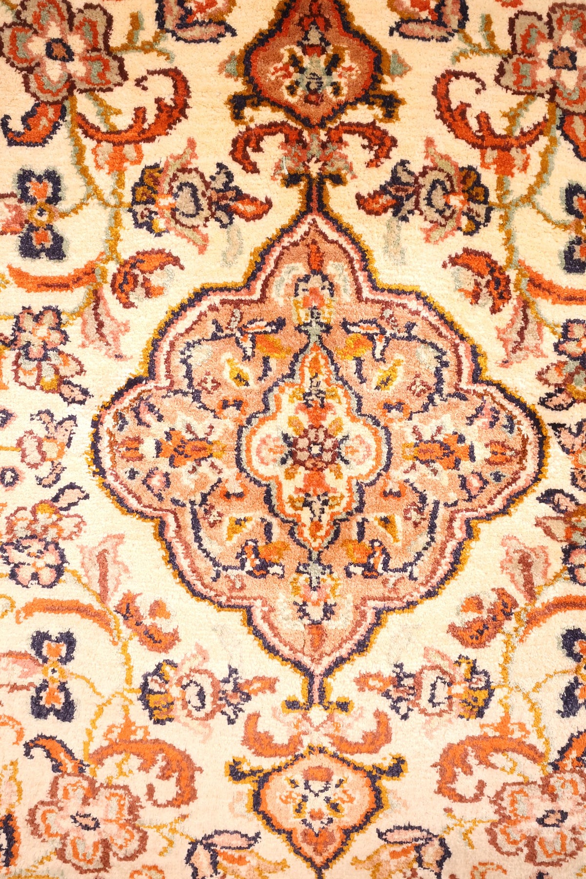 Détail du médaillon losangé rose saumon et des rinceaux fleuris du tapis Cachemire