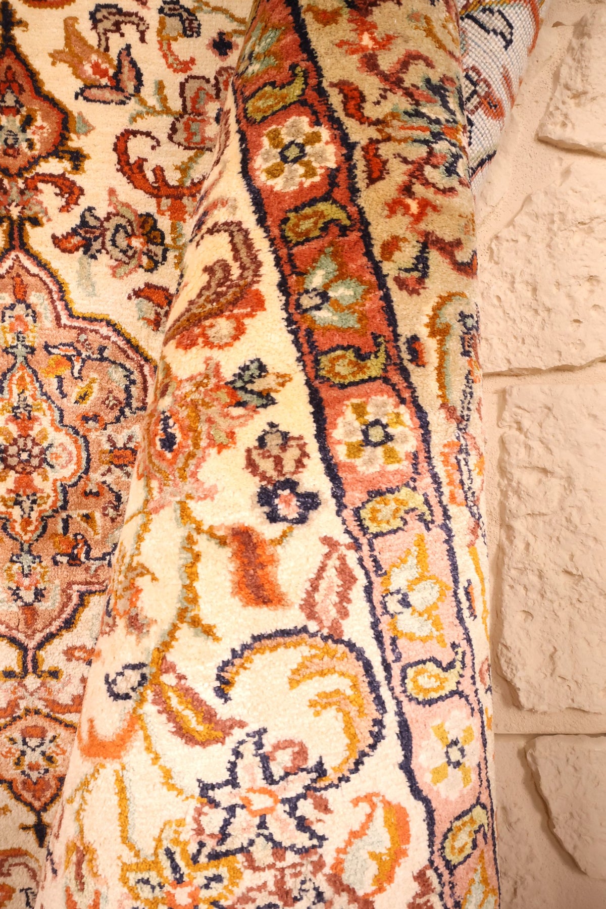 Lisière du tapis Cachemire beige, rinceaux orange et liseré bleu nuit le long du bord
