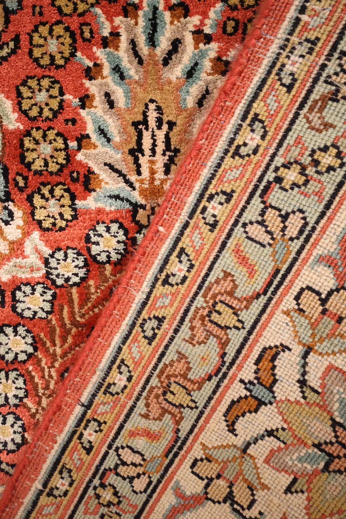 Coin replié du tapis Cachemire, contre-bordures vertes et noires bien visibles