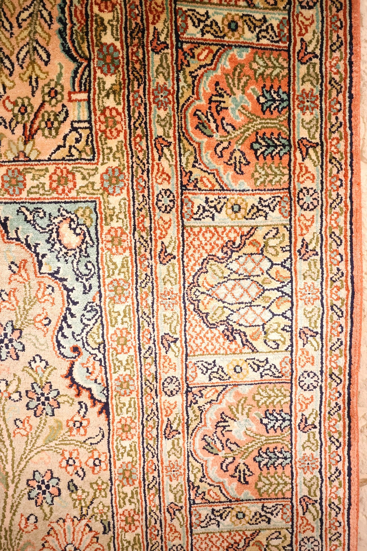 Détail des bordures à cartouches beige et orange du tapis Cachemire en soie
