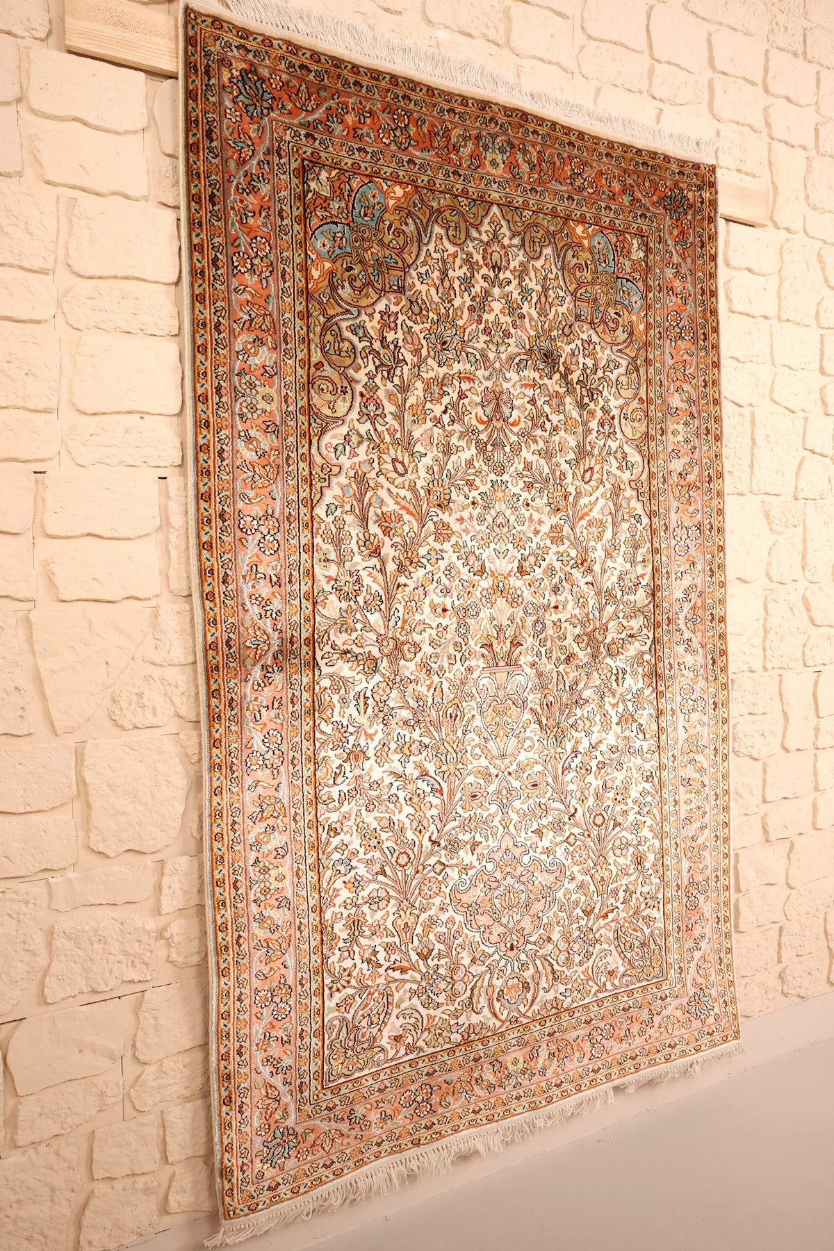 Tapis Cachemire beige et orange vu de biais, champ fleuri et bordure rose saumon