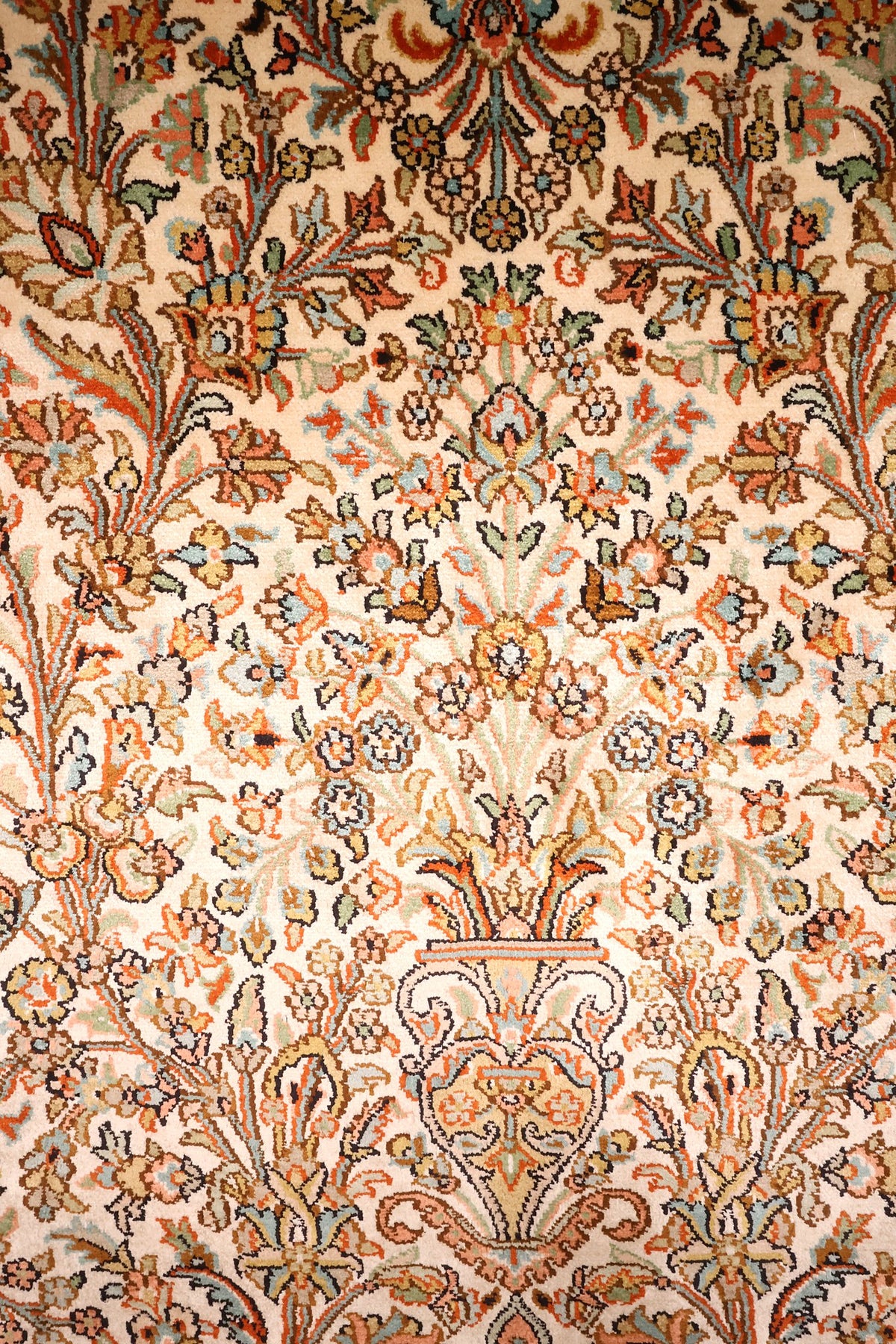 Détail des vases et tiges fleuries du tapis Cachemire, tons orange, bleu et vert
