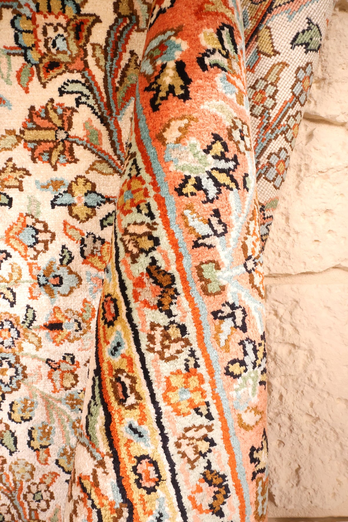 Coin replié du tapis Cachemire en soie, bordure orange et envers apparent