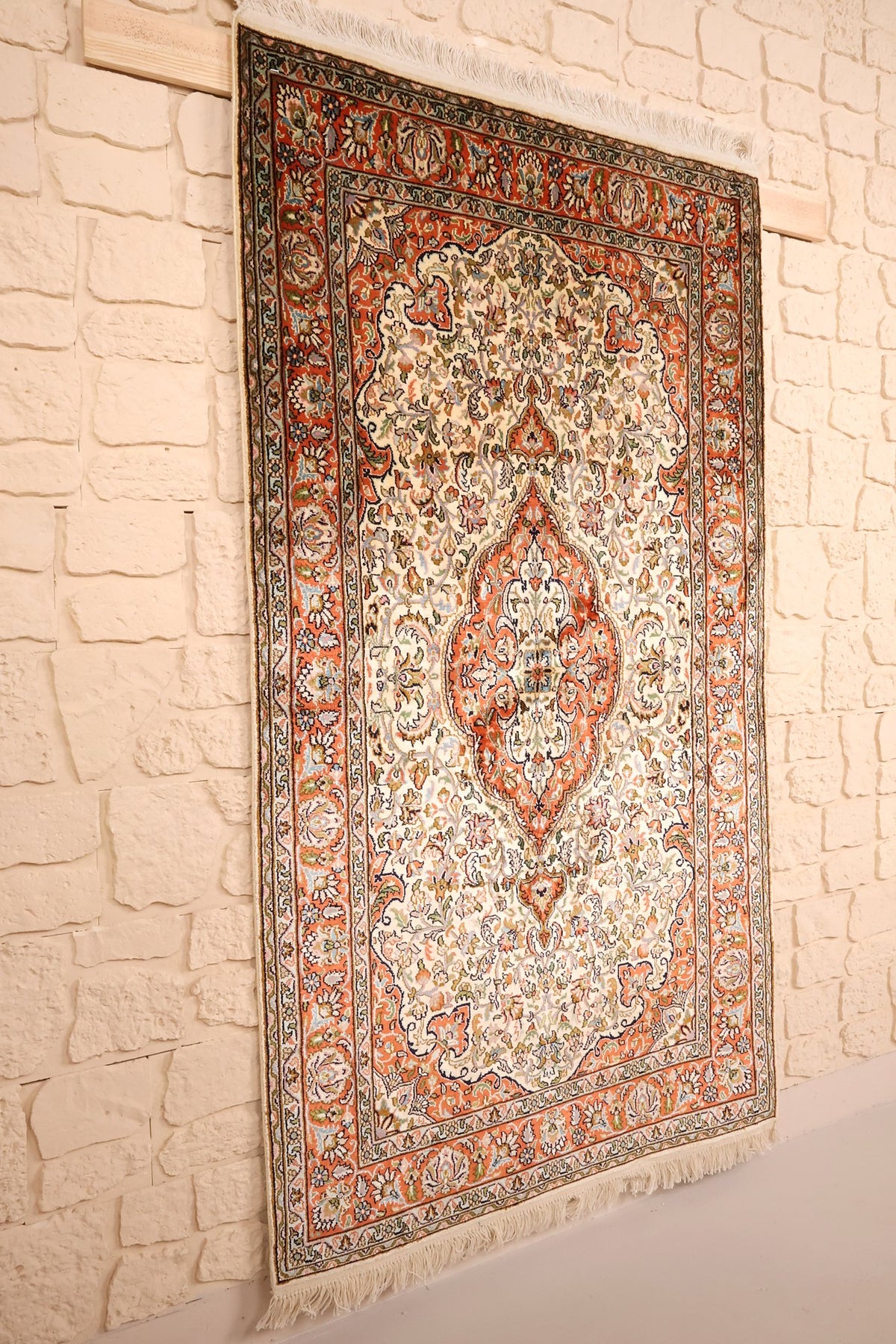 Vue de biais du tapis Cachemire beige et orange, médaillon central à pendentifs
