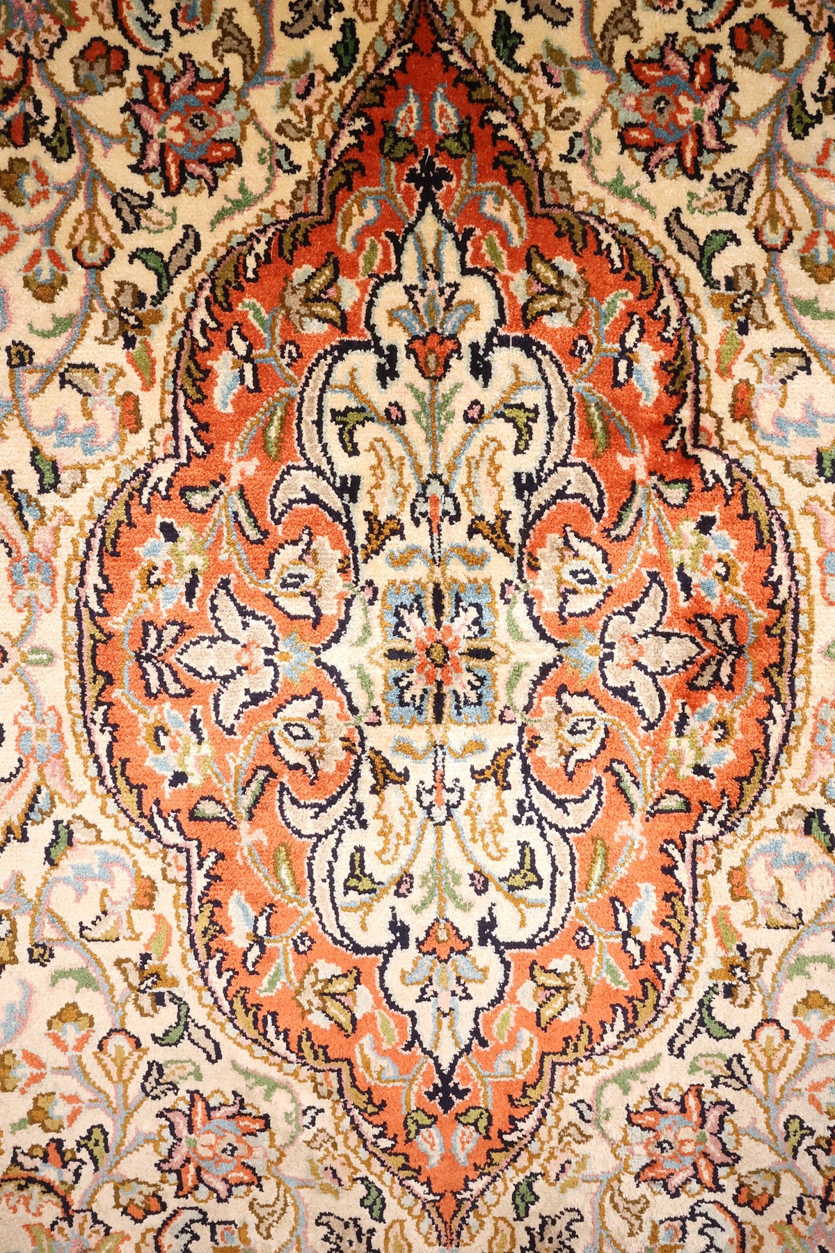 Détail du médaillon orange et des rinceaux fleuris du tapis Cachemire en soie