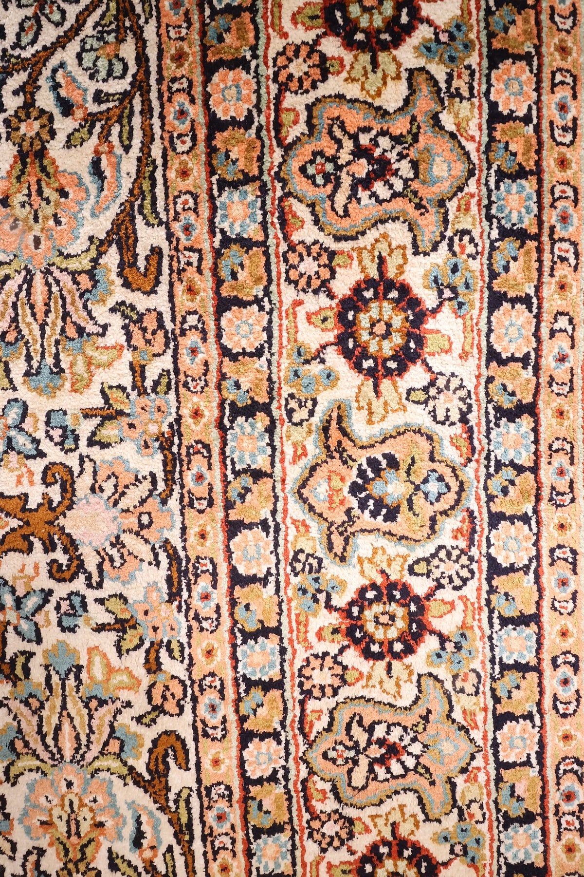 Bordure bleu nuit à palmettes et rosettes saumon du tapis Cachemire