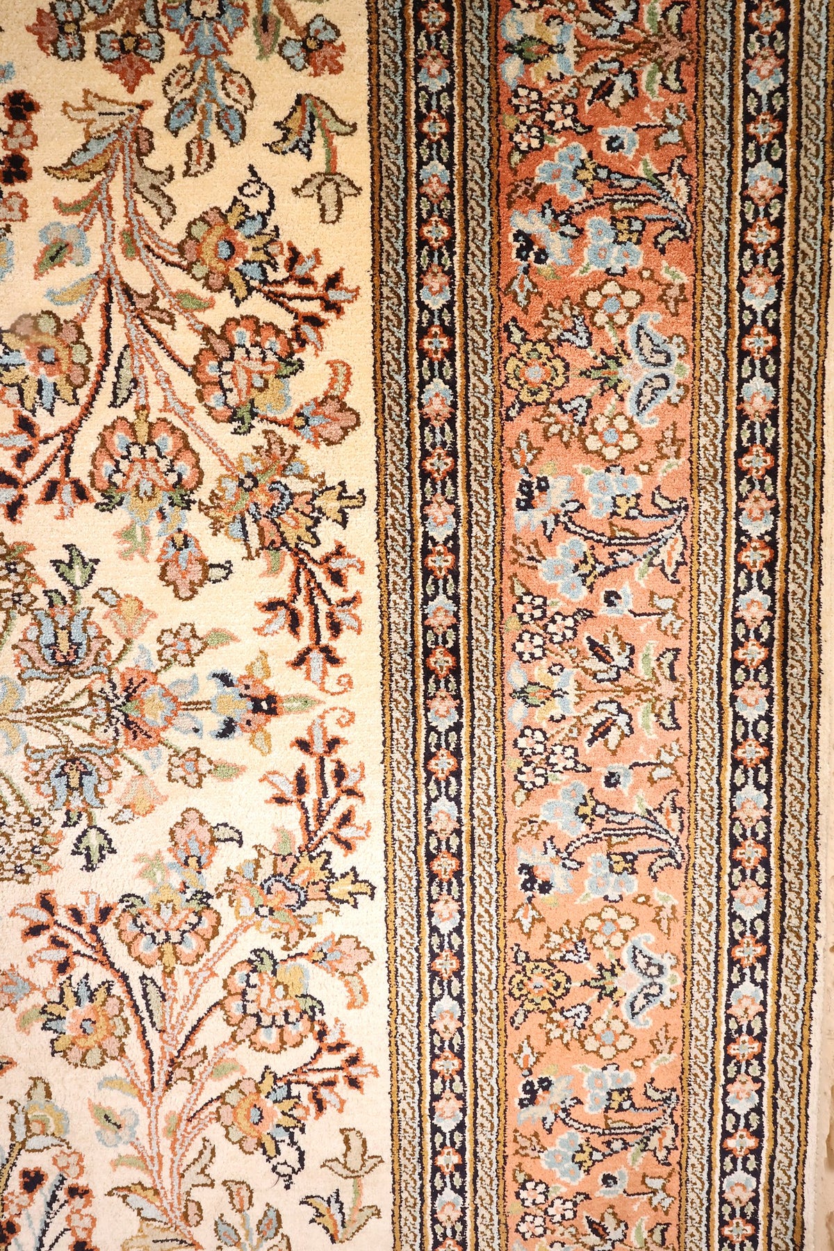 Bordure orange à rinceaux fleuris et contre-bordures beige et bleu nuit du tapis Cachemire