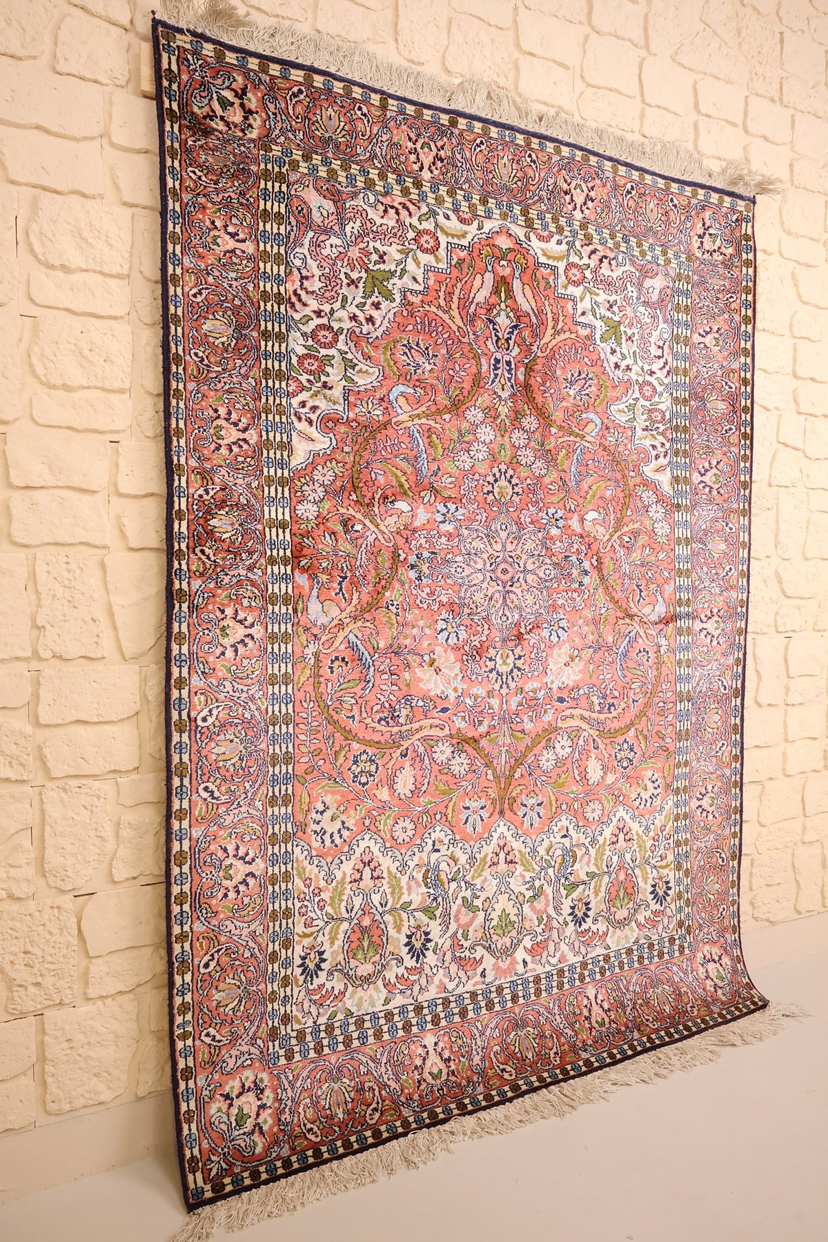 Tapis Cachemire rose et bleu vu de biais, écoinçons ivoire à décor floral