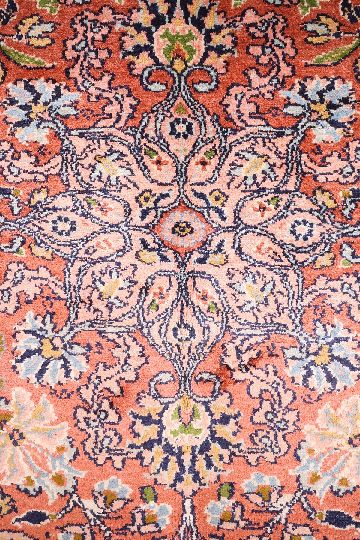 Détail des rinceaux fleuris et palmettes sur champ rose saumon du tapis Cachemire