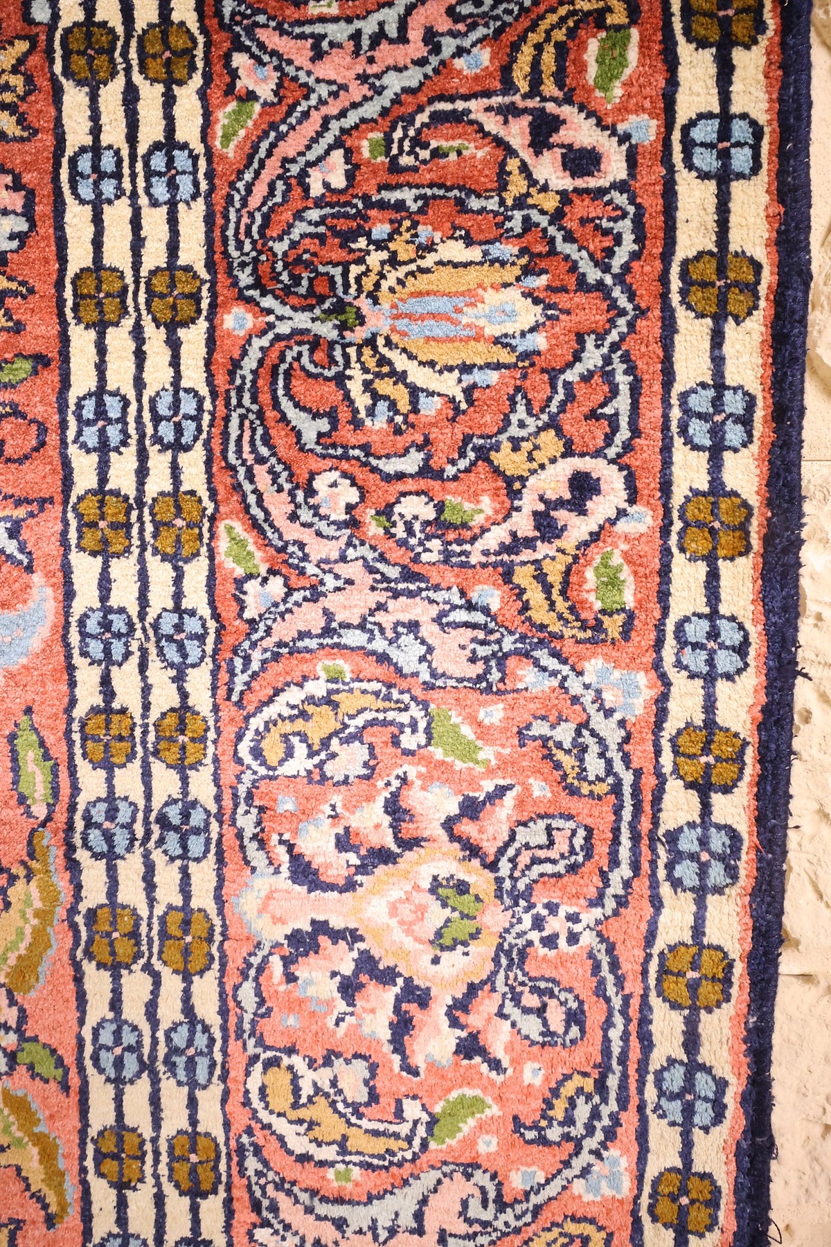 Bordure rose à boteh et contre-bordure ivoire à rosettes bleues et ocre