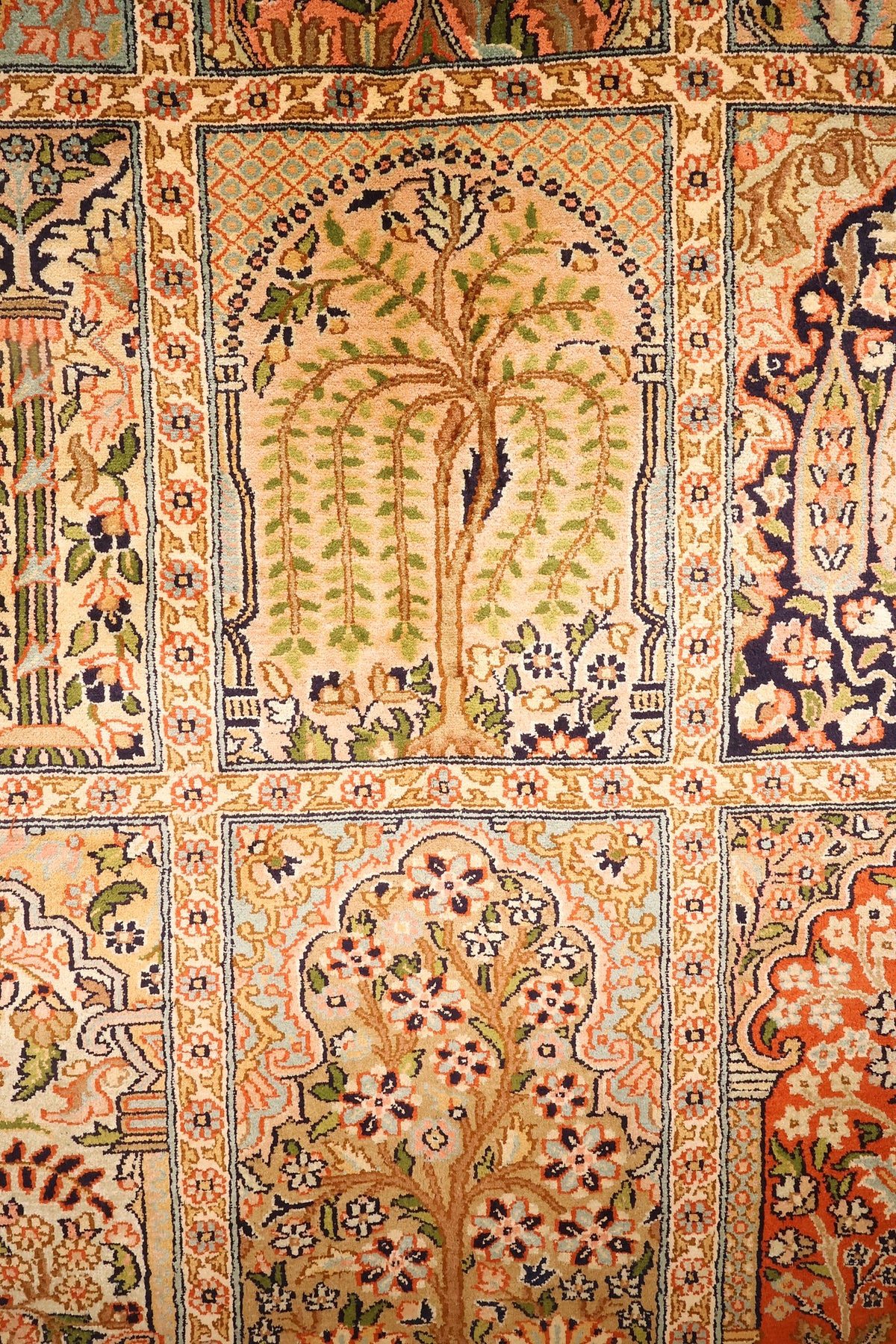 Détail d'un compartiment à arbre fleuri vert et saumon du tapis Cachemire beige