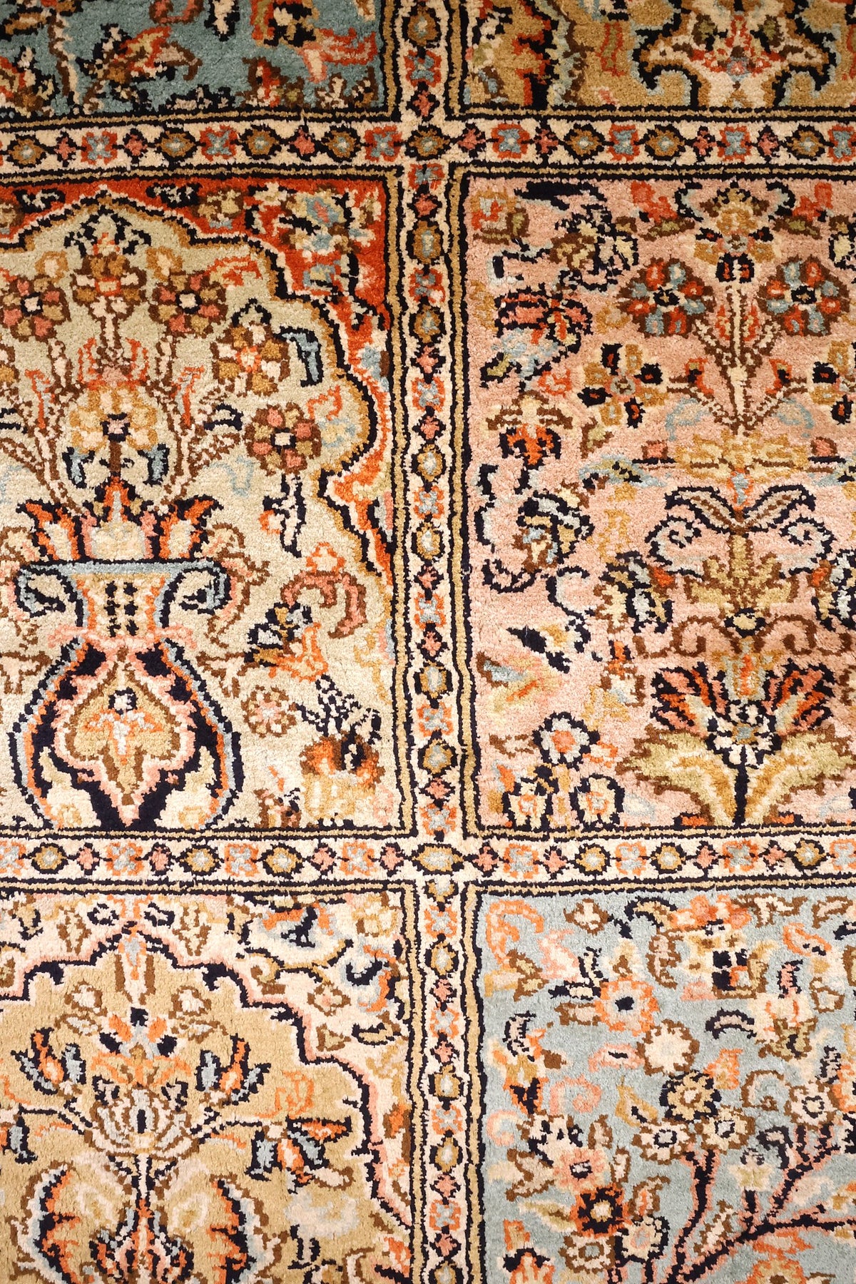 Détail des compartiments beige, rose et bleu avec vases fleuris du tapis Cachemire