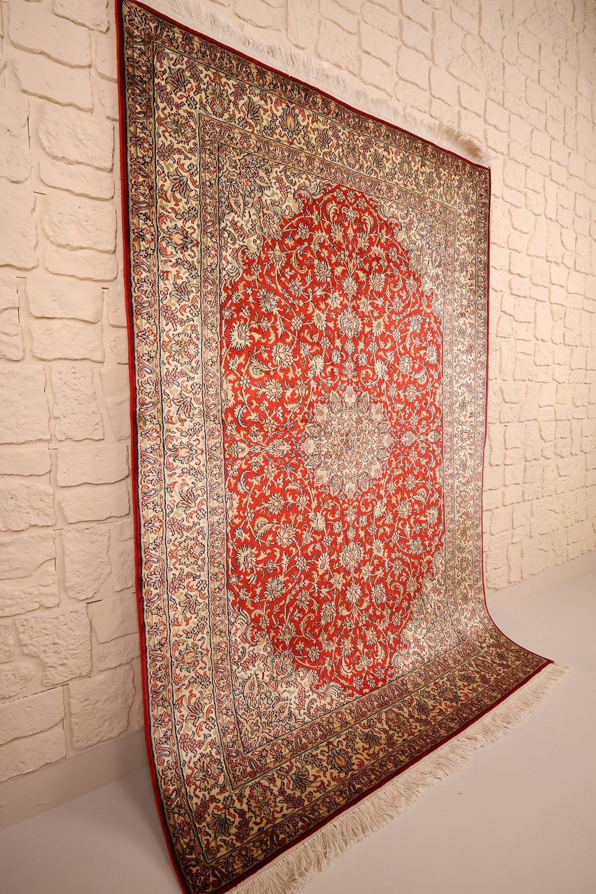 Tapis Cachemire rouge et ivoire vu de biais, champ fleuri et bordure à palmettes