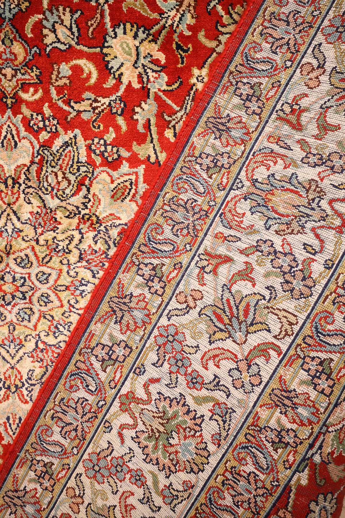 Coin du tapis Cachemire en soie nouée main, passage du champ rouge à la bordure
