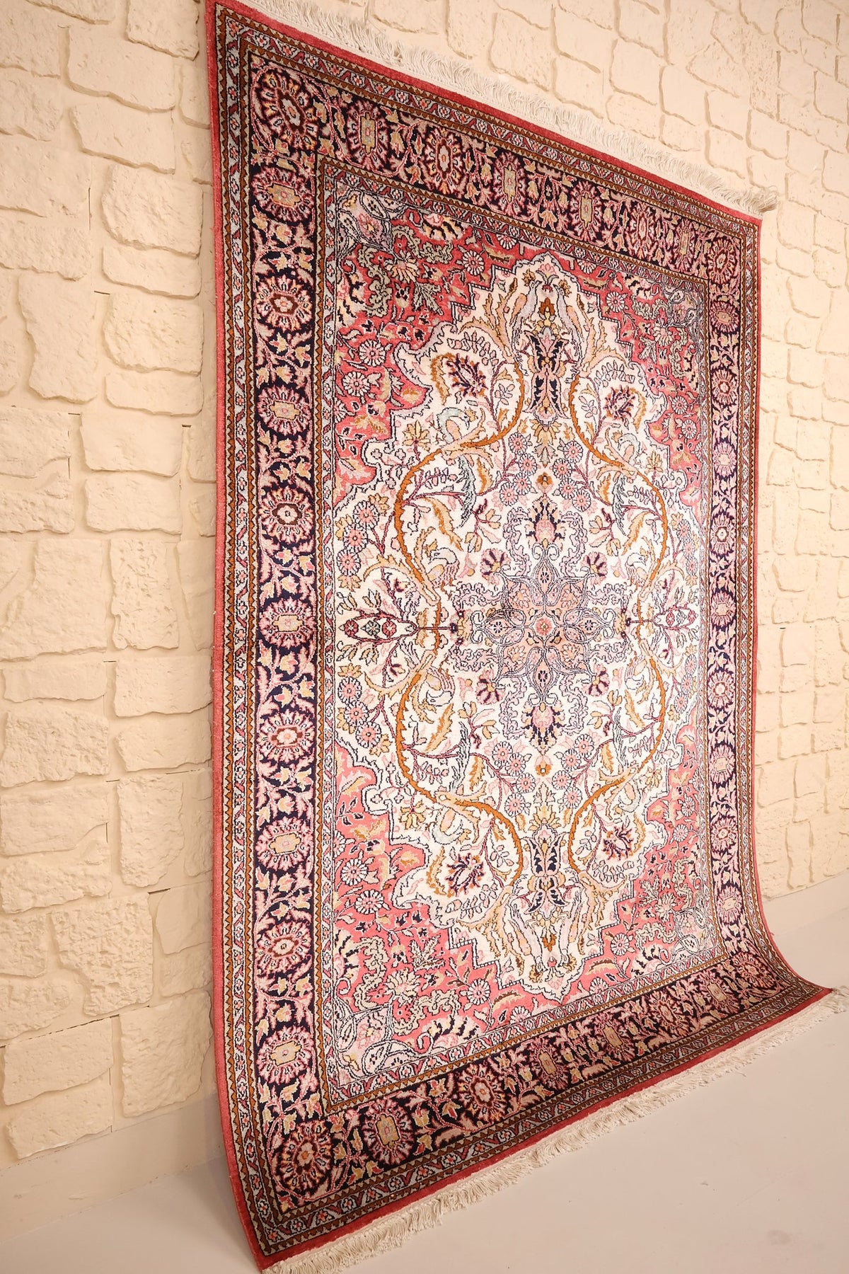 Tapis Cachemire en soie noué à la main, vue de biais sur le champ ivoire et la bordure bleu nuit