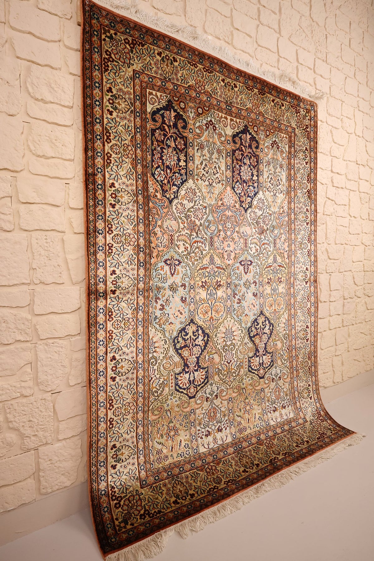 Tapis Cachemire beige et orange vu de biais, cartouches bleu nuit et franges écrues