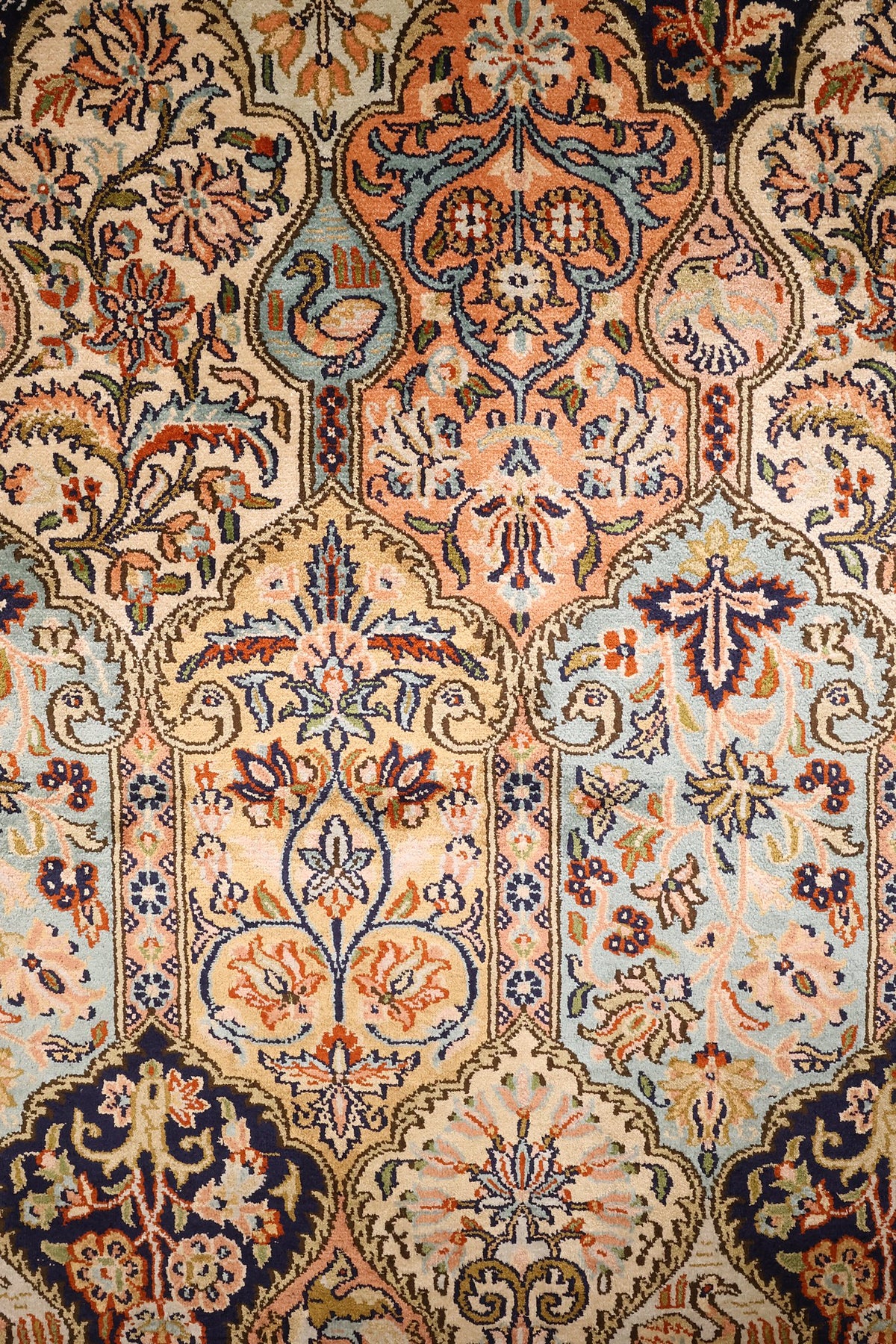 Détail des niches fleuries et des oiseaux du tapis Cachemire beige à rose saumon