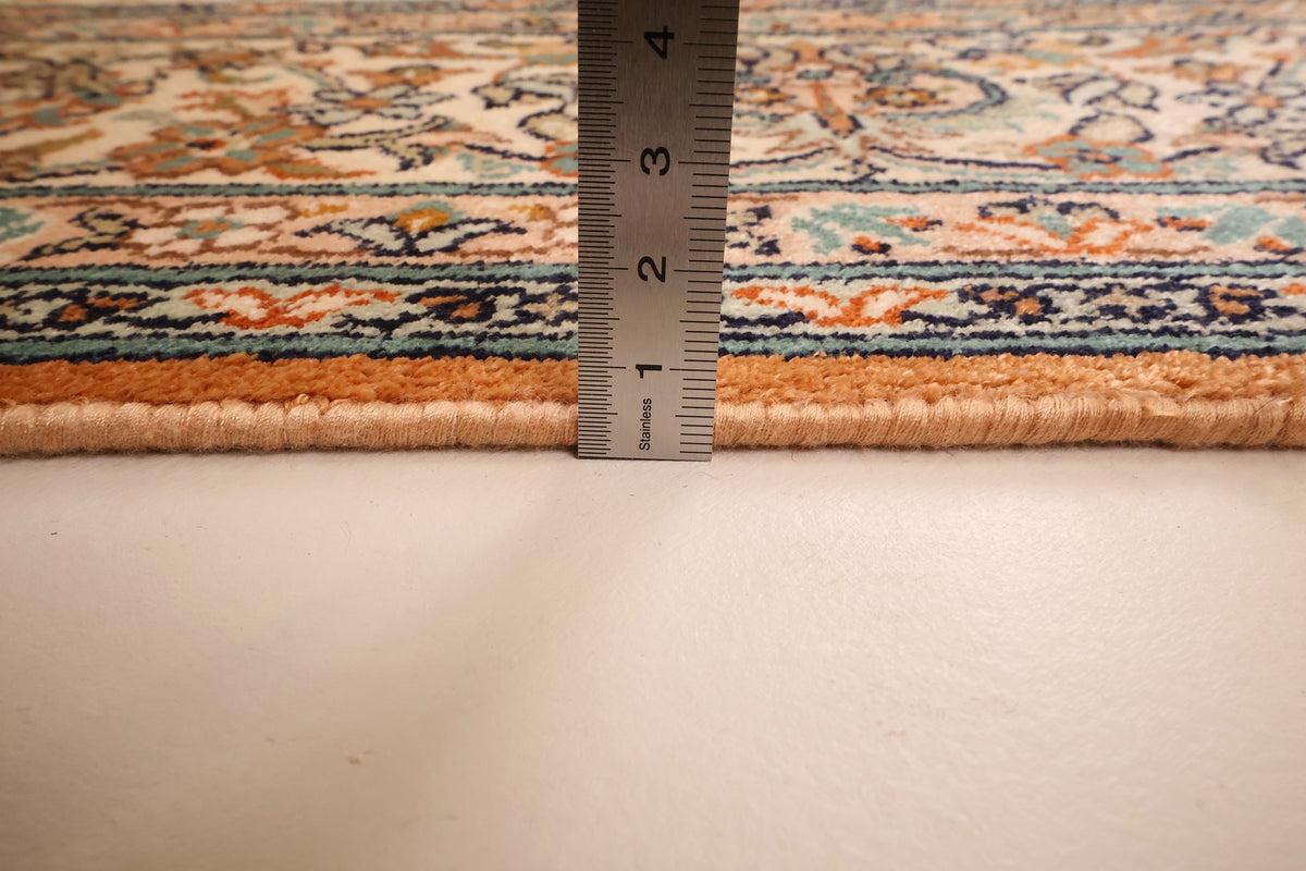 Mesure de l'épaisseur du tapis Cachemire en soie contre la lisière orangée